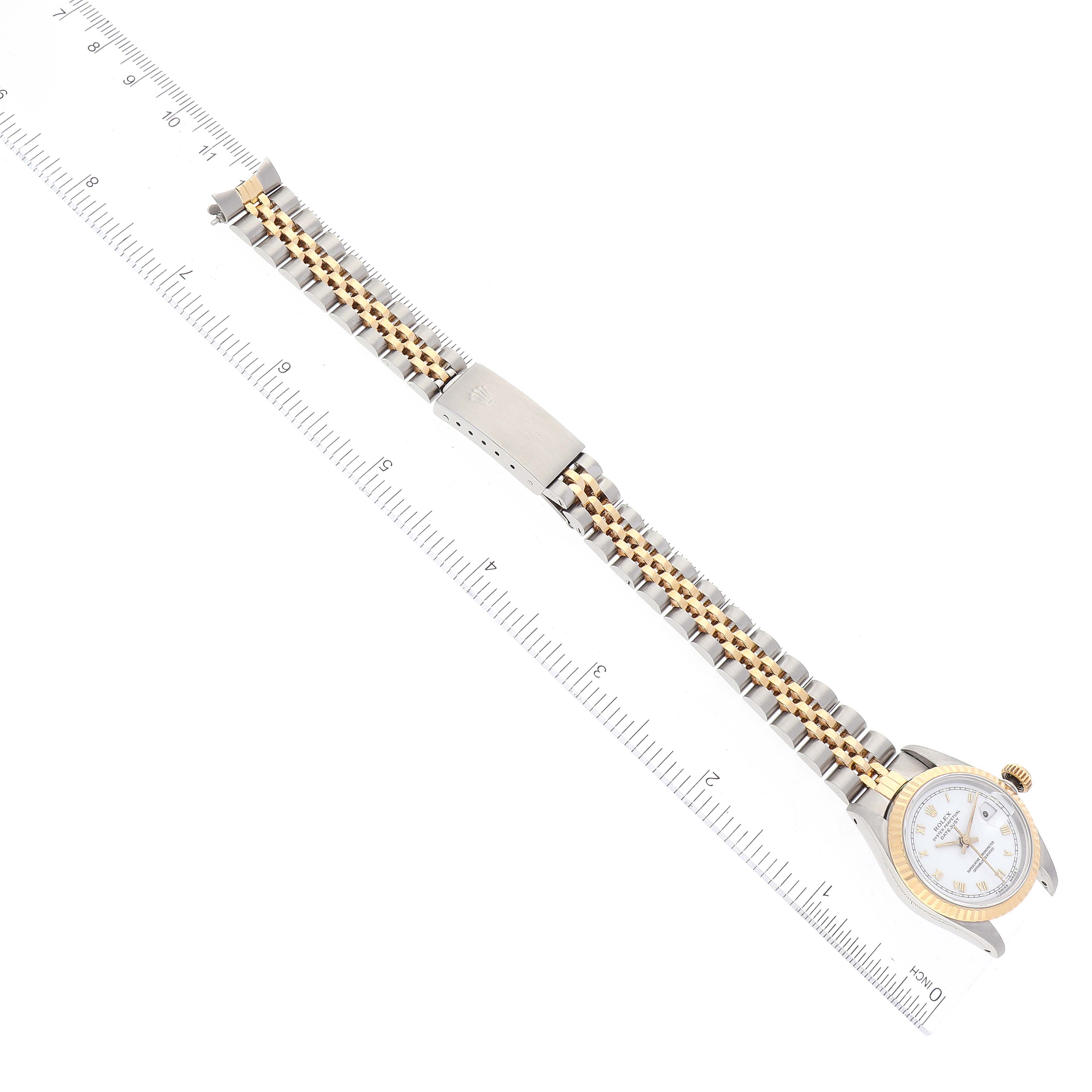 This image shows a Rolex Datejust 69173 Women's Steel and Gold (two tone) White Dial 69173 Women's Steel and Gold (two tone) White Dial watch laid flat alongside a ruler, displaying its band and face from a top-down angle.
