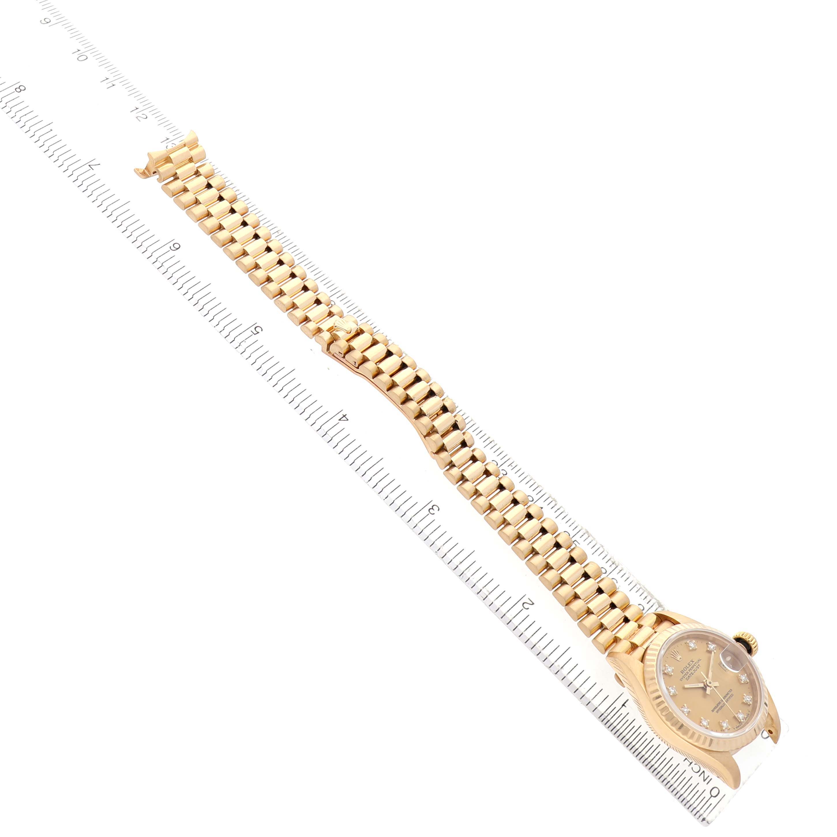 The Rolex Datejust 69178 Women's Yellow Gold Champagne Dial watch is shown from an overhead angle, displaying its face and full bracelet aligned with a ruler.