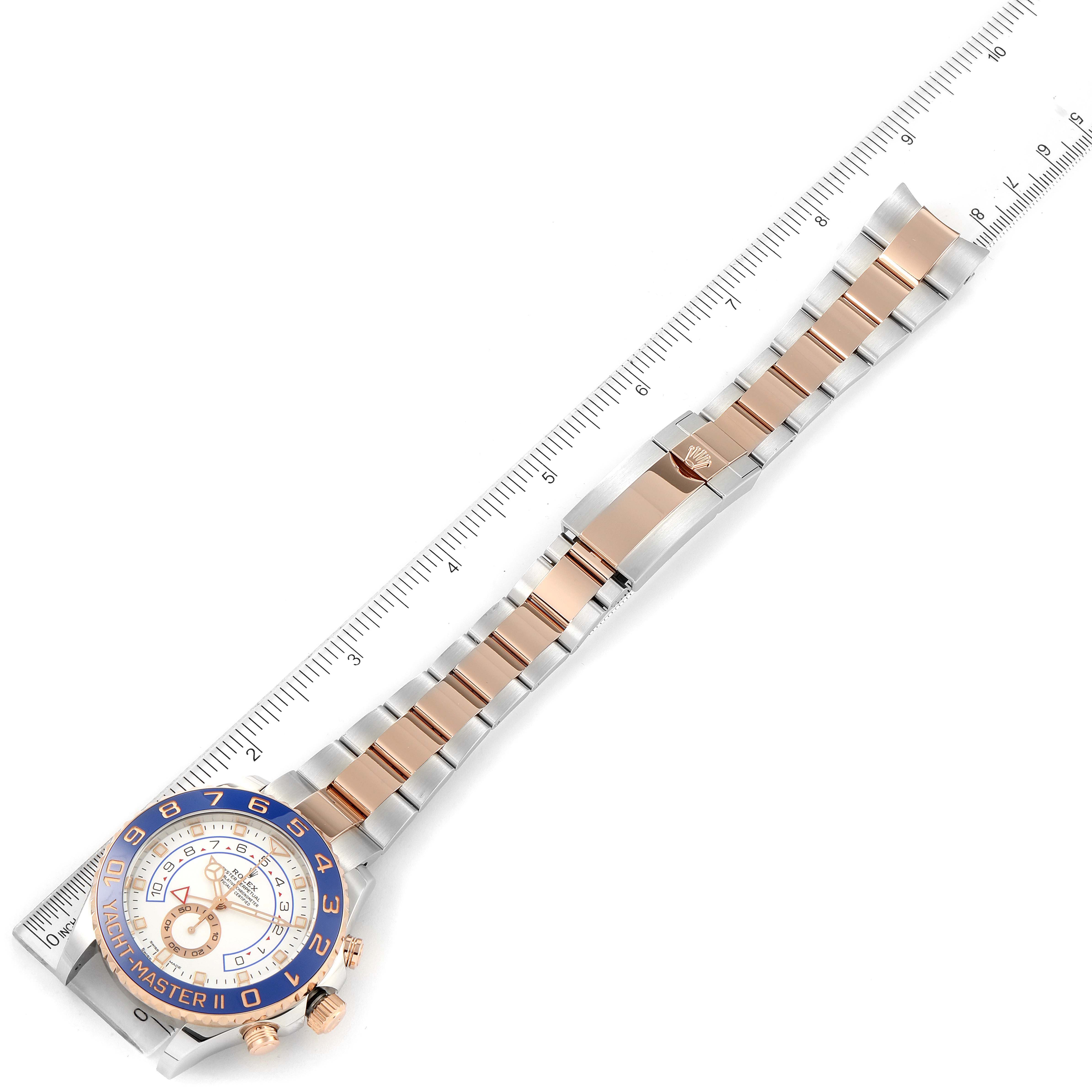 The image shows a Rolex Yacht-Master 116681 Men
s Steel and Gold (two tone) White Dial 116681 Men
s Steel and Gold (two tone) White Dial watch laid flat with a ruler alongside, displaying the band and face from a top-down angle.