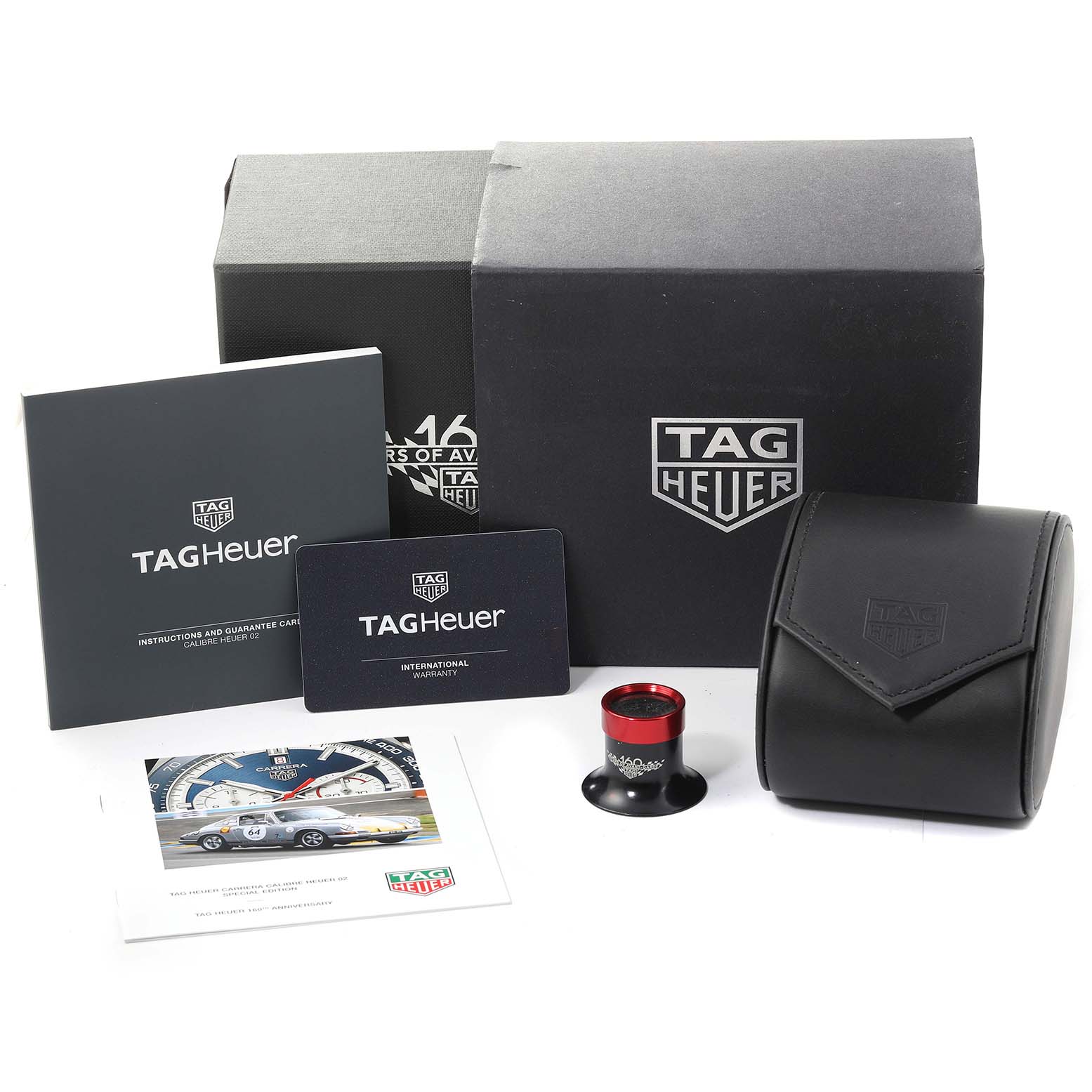 The image shows the packaging and accessories for a Tag Heuer Carrera CBN2A1E.BA0643 Men's Stainless Steel Blue Dial CBN2A1E.BA0643 Men's Stainless Steel Blue Dial watch, including boxes, warranty cards, and a small red magnifier.