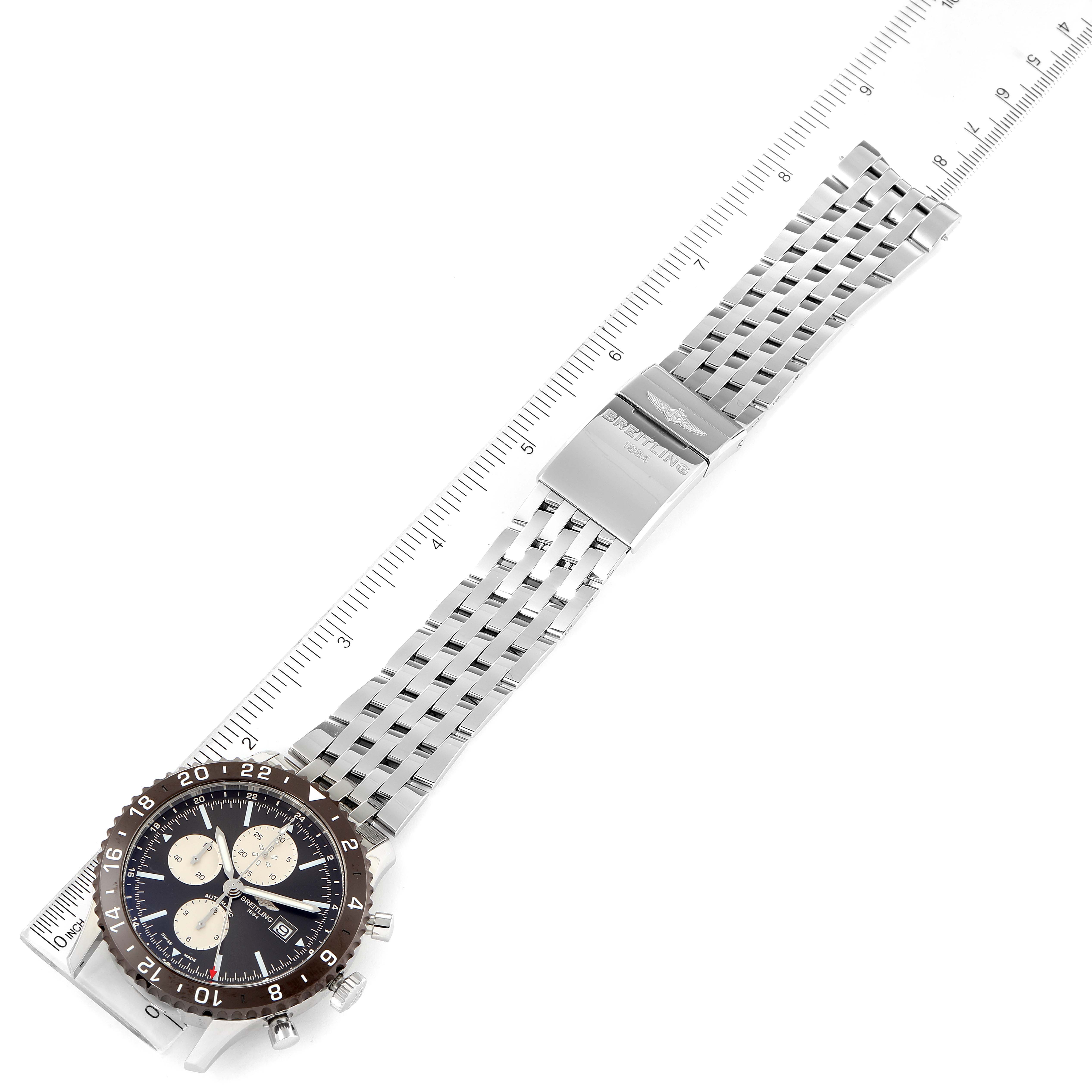 The image shows a Breitling Chronoliner Y24310 Men's Stainless Steel Brown Dial Y24310 Men's Stainless Steel Brown Dial watch laid flat with its face and metal bracelet fully visible, alongside a ruler for scale.
