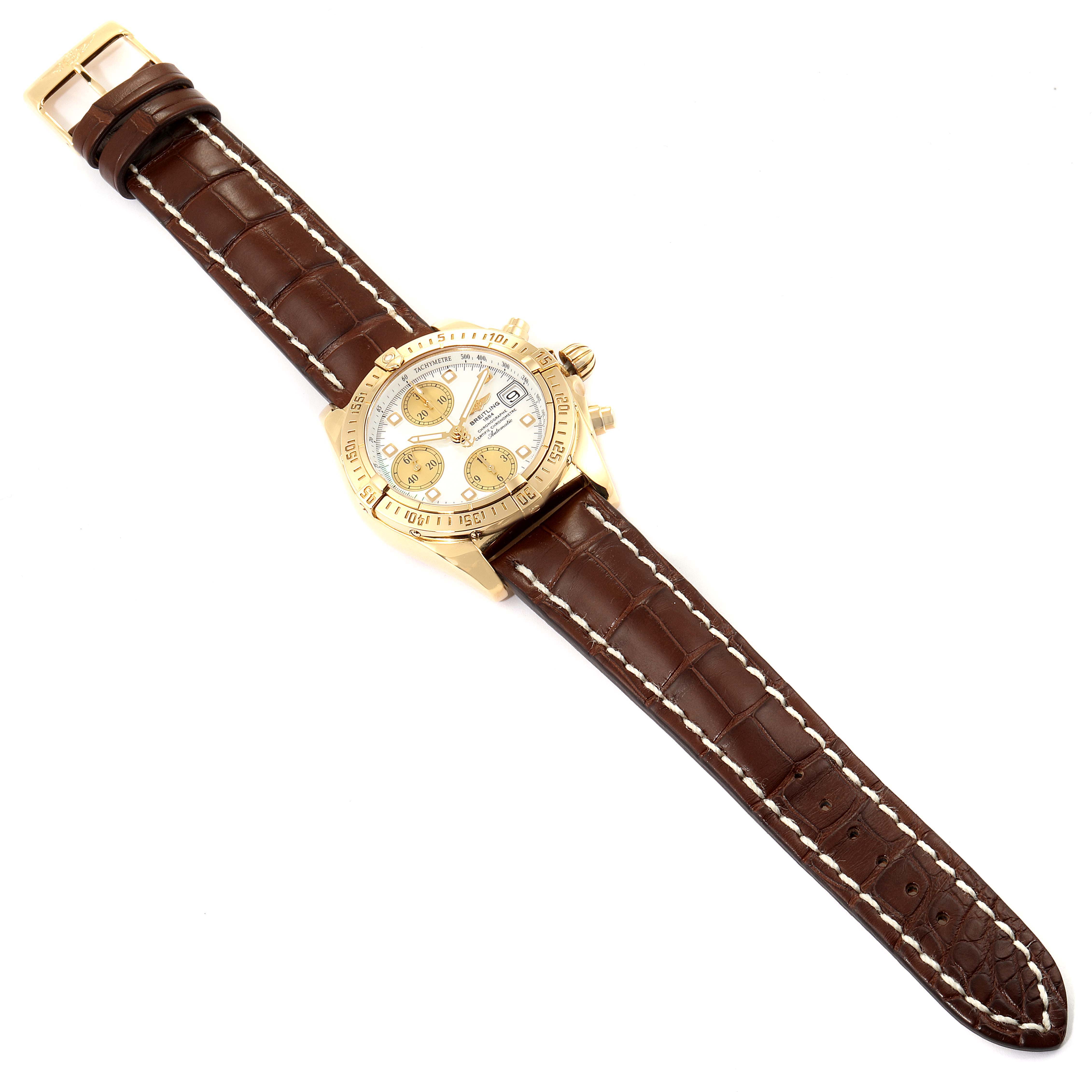 The Breitling Windrider K13358 Men's Yellow Gold Mother of Pearl Dial K13358 Men's Yellow Gold Mother of Pearl Dial model watch is shown from a top-down angle, featuring a gold case and brown leather strap.