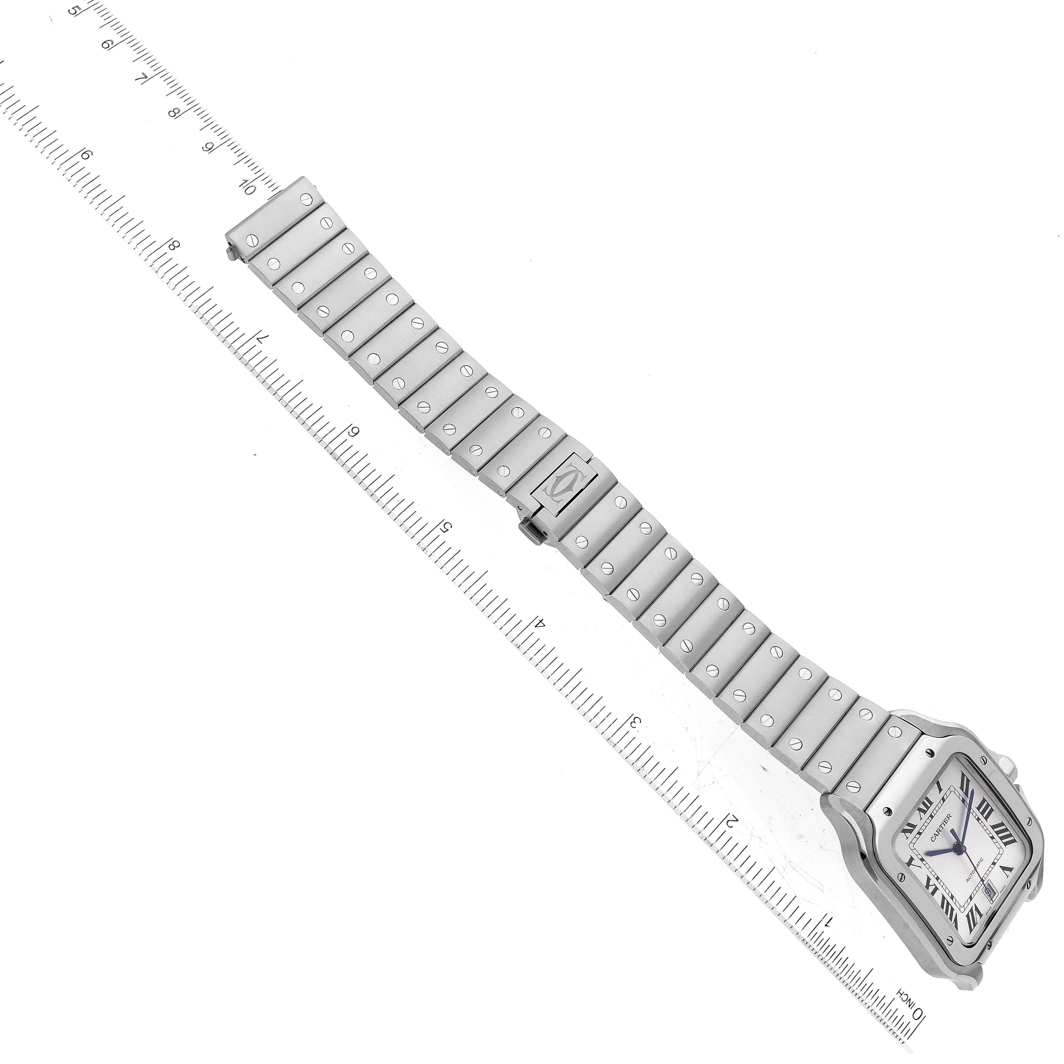 This image shows the Cartier Santos WSSA0018 Men
s Stainless Steel Silver Dial WSSA0018 Men
s Stainless Steel Silver Dial watch laid flat with a prominent view of its face, bracelet, and clasp next to a ruler for scale.