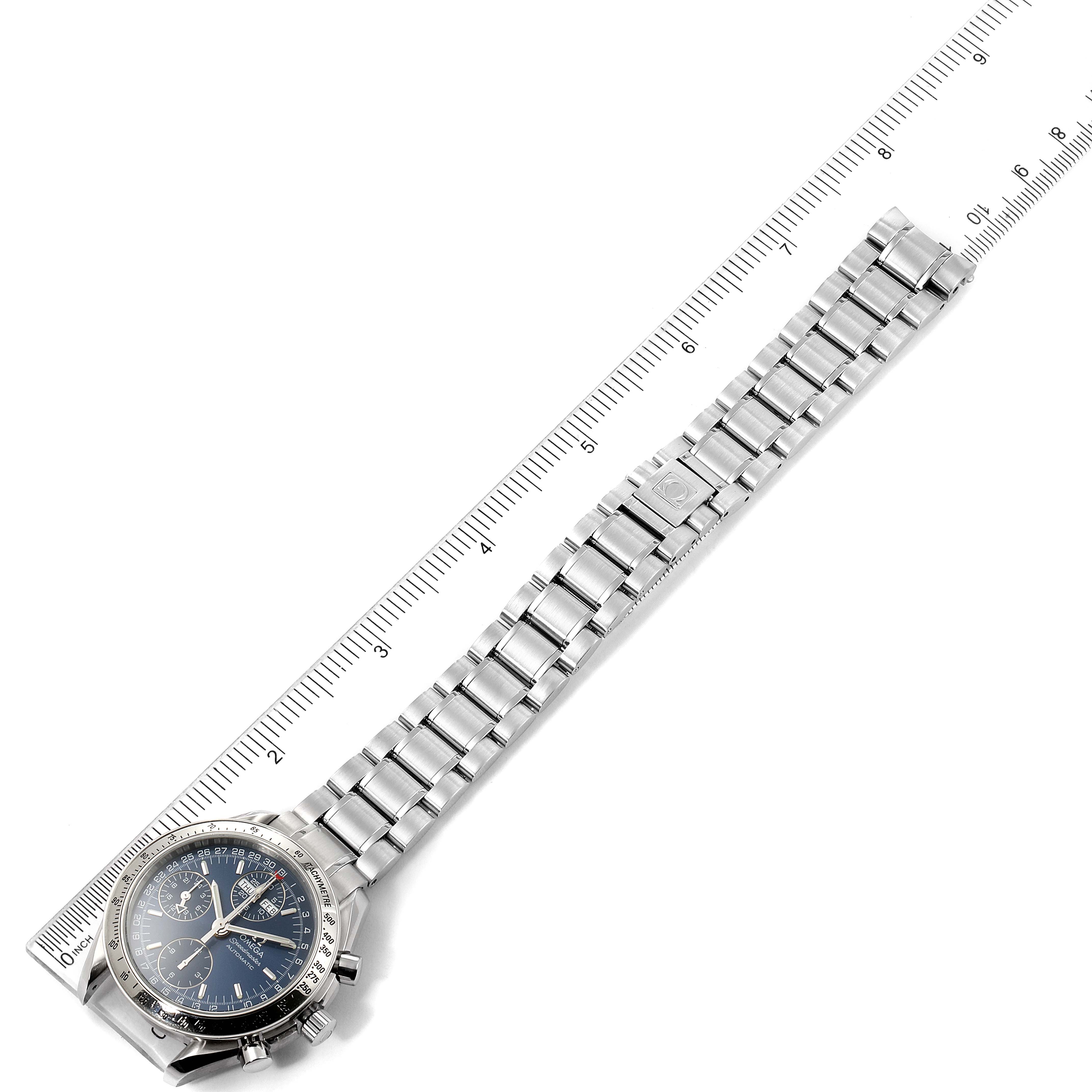 The image shows an Omega Speedmaster 3523.80.00 Men
s Stainless Steel Blue Dial 3523.80.00 Men
s Stainless Steel Blue Dial watch with a silver metal bracelet, laid flat beside a ruler for scale.