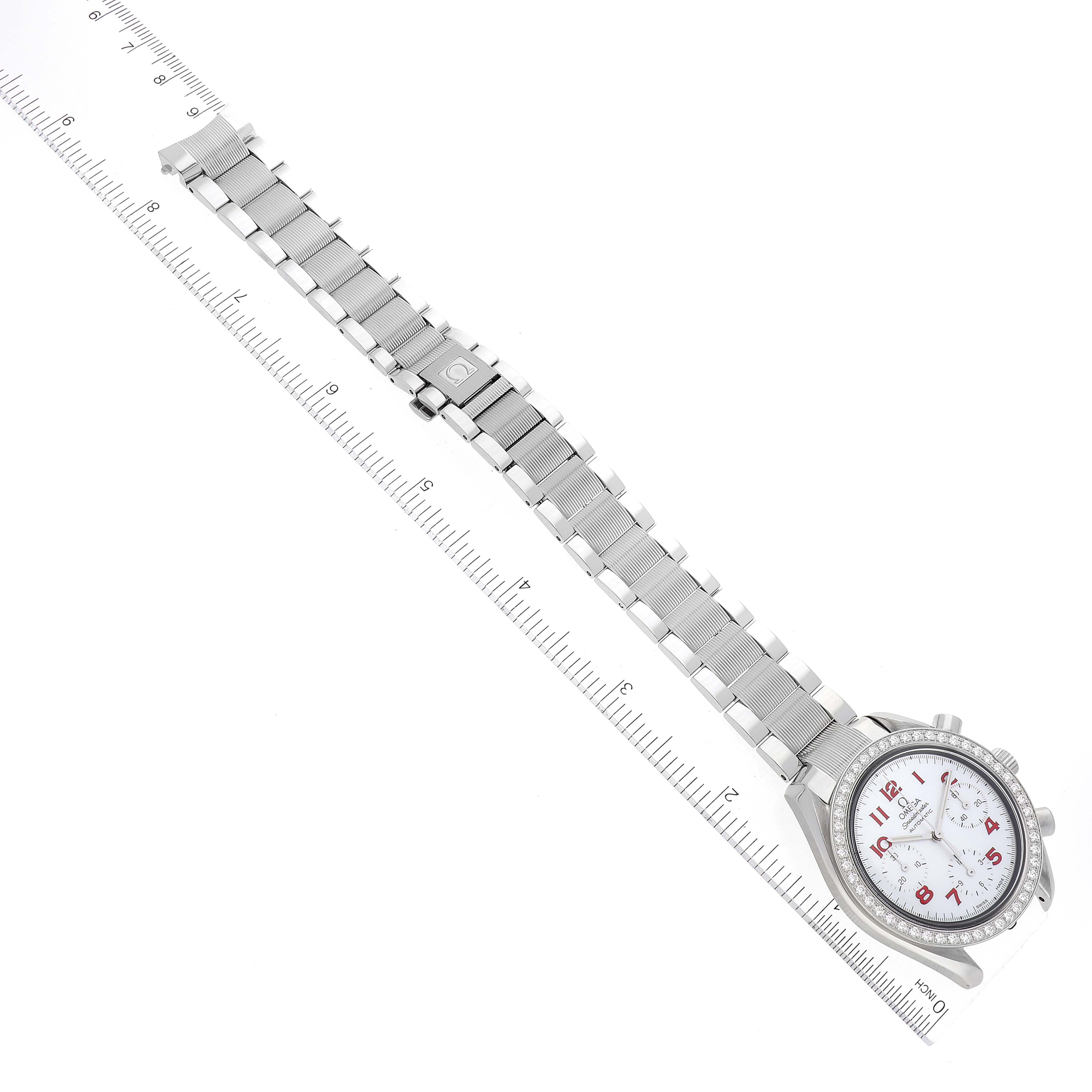 The image shows an overhead view of an Omega Speedmaster 3515.79.00 Men's Stainless Steel Mother of Pearl Dial 3515.79.00 Men's Stainless Steel Mother of Pearl Dial watch, highlighting its face and stainless steel bracelet placed on a ruler.