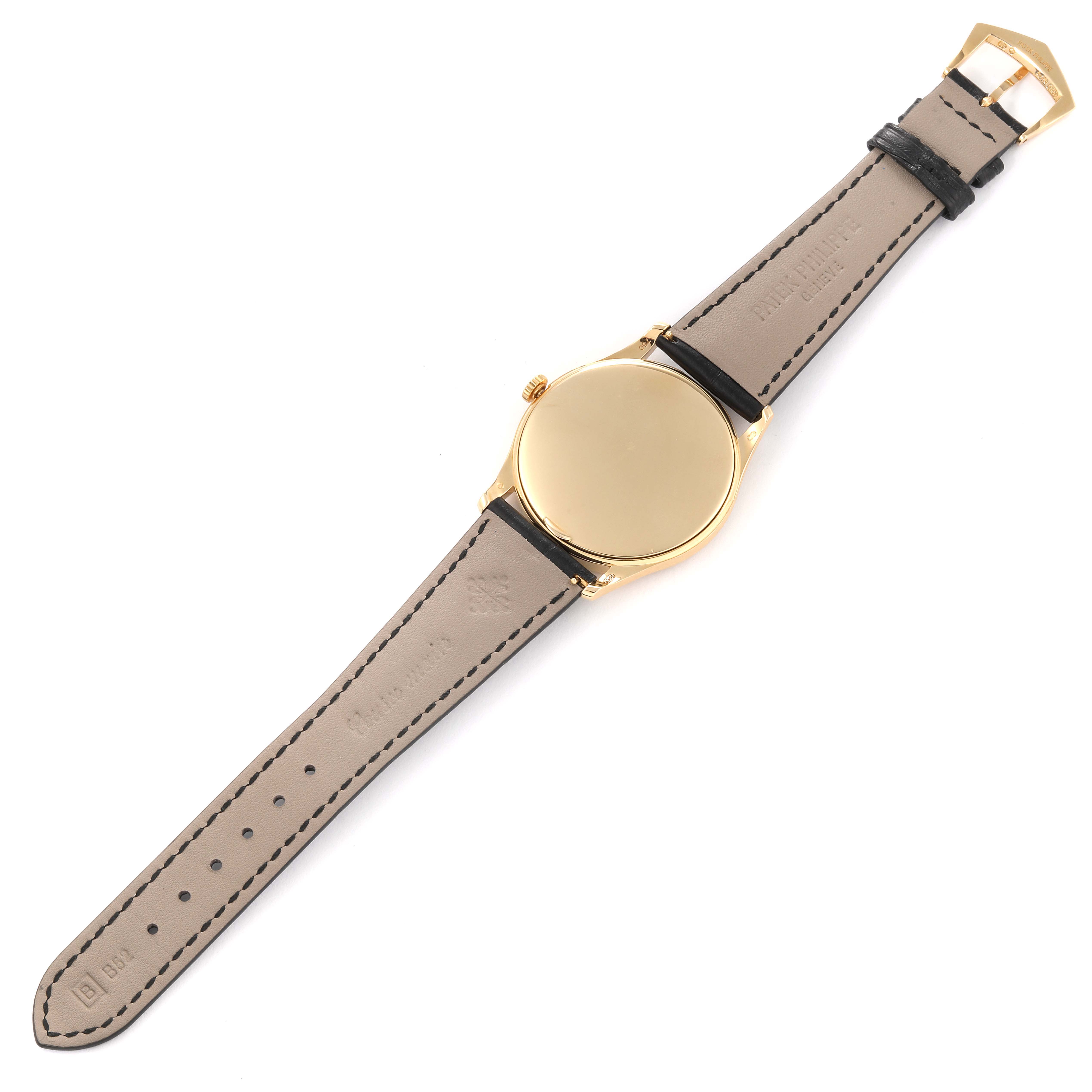 The Patek Philippe Calatrava 5196J Men's Yellow Gold Silver Dial 5196J Men's Yellow Gold Silver Dial watch is shown from the back, displaying its gold case, leather strap, and buckle.
