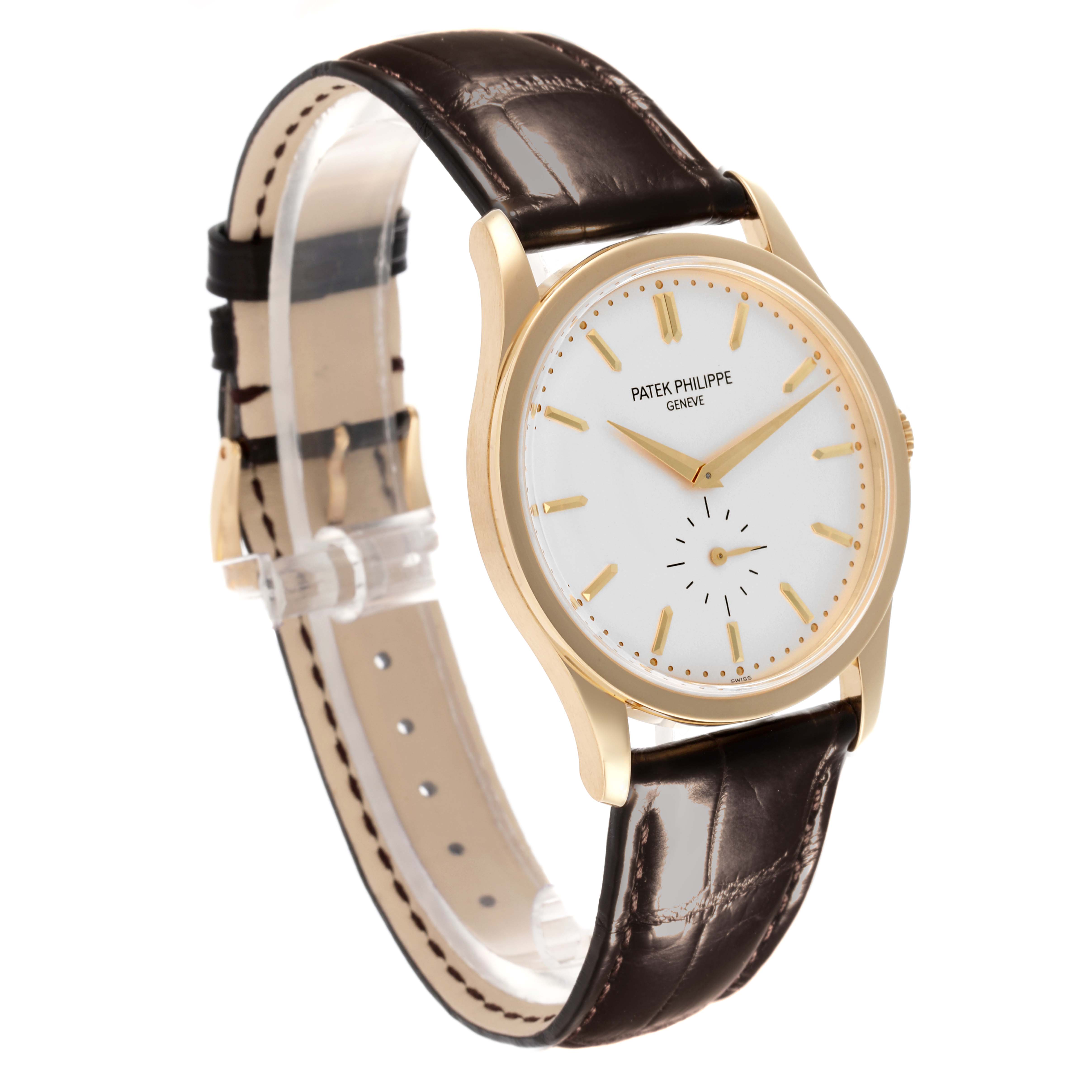 The Patek Philippe Calatrava 5196J Men's Yellow Gold Silver Dial 5196J Men's Yellow Gold Silver Dial watch is shown at a three-quarter angle, highlighting the gold case, white dial, and brown leather strap.