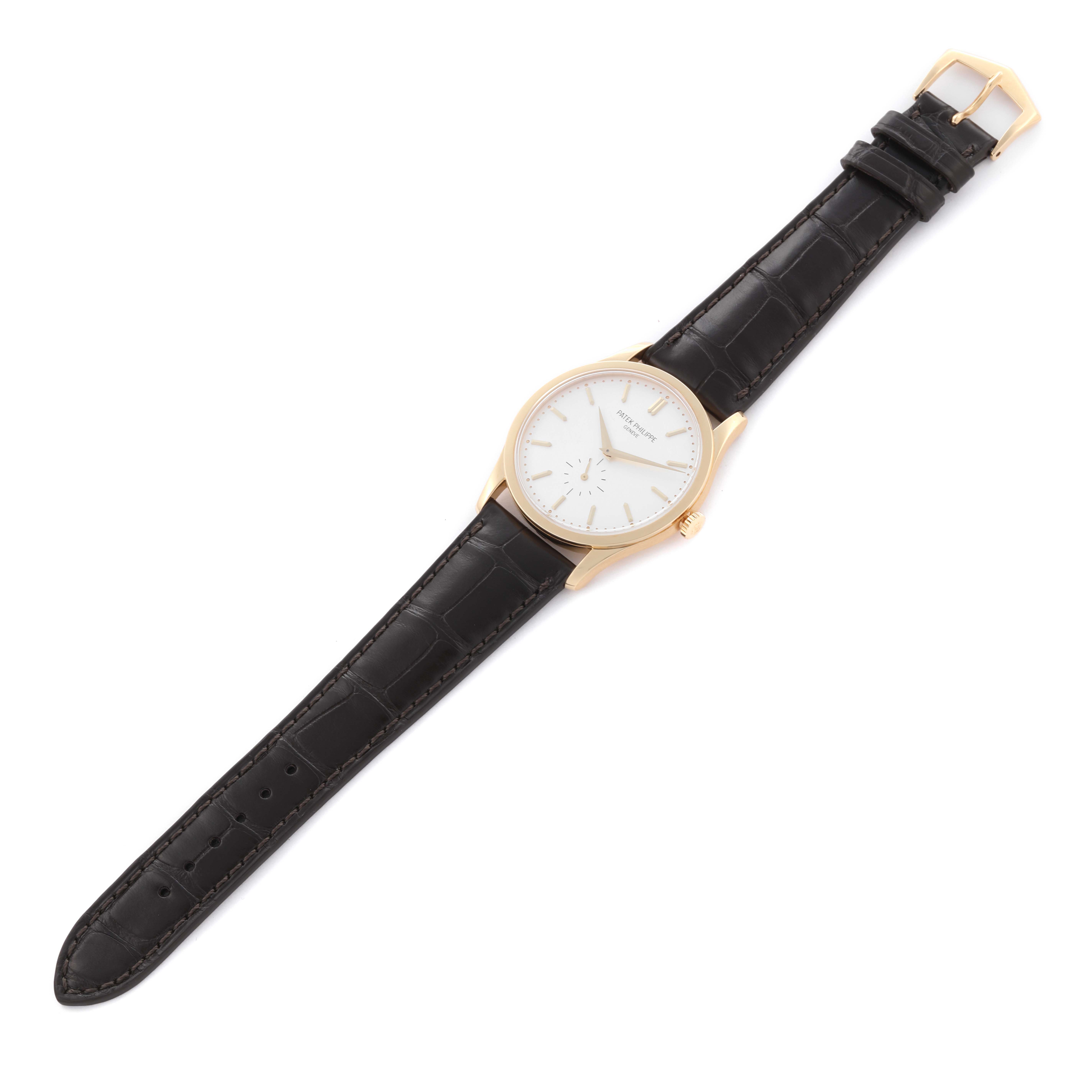 The Patek Philippe Calatrava 5196J-001 Men's Yellow Gold Silver Dial 5196J-001 Men's Yellow Gold Silver Dial watch is shown from a top-down angle, displaying the face, gold case, and black leather strap.