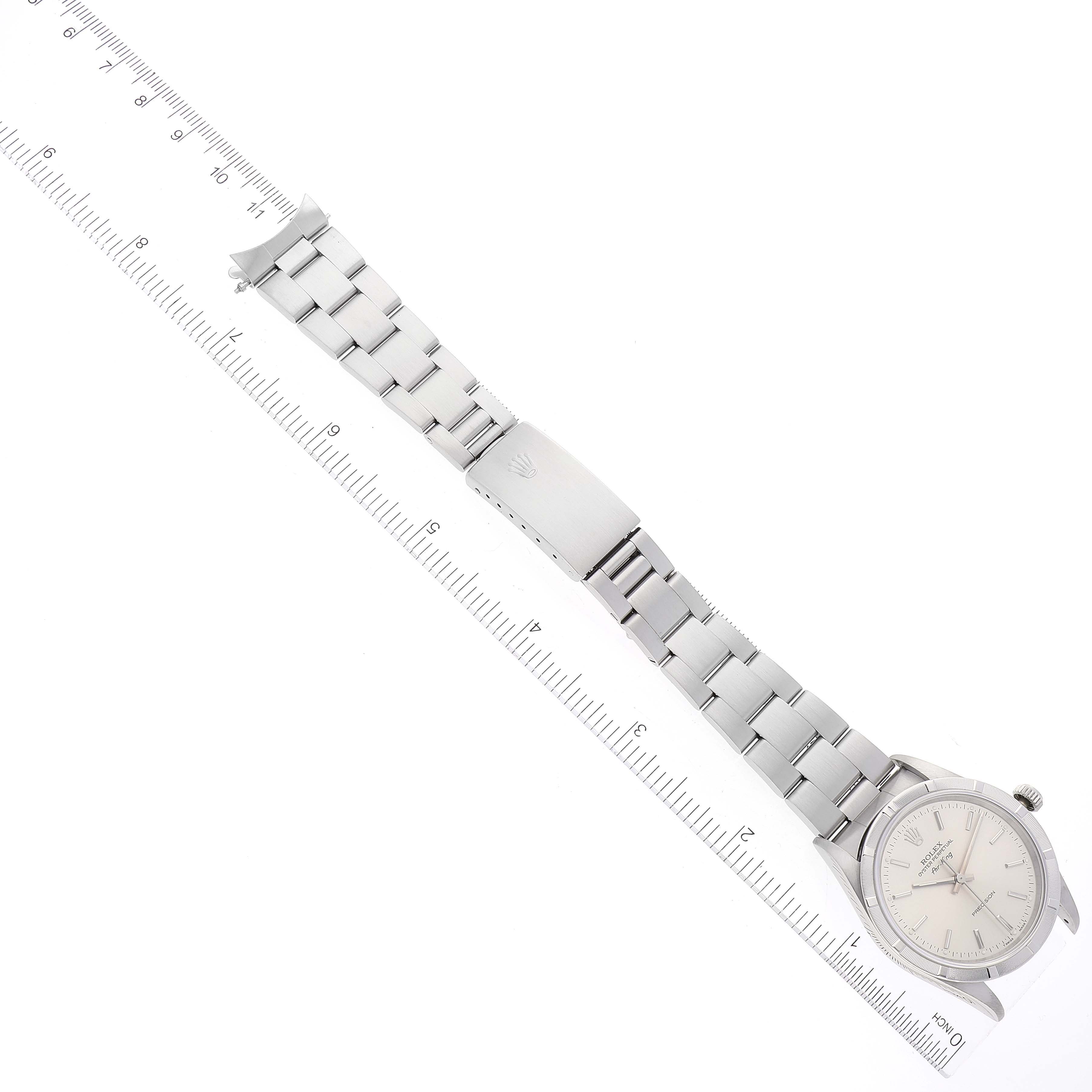 The image shows a top-down view of a Rolex Air-King 14010 Men's Stainless Steel Silver Dial 14010 Men's Stainless Steel Silver Dial watch, displaying its face, bracelet, and clasp, alongside a ruler.