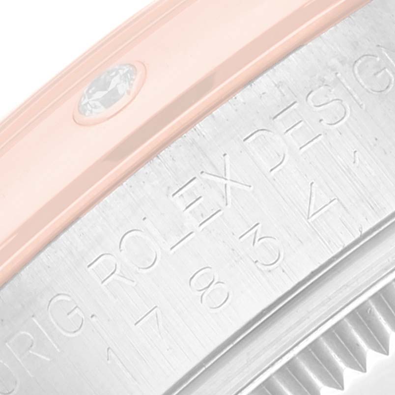 This close-up image of a Rolex Mid-Size 178341 Women's Steel and Gold (two tone) Mother of Pearl Dial 178341 Women's Steel and Gold (two tone) Mother of Pearl Dial watch shows the detailed engraving and part of the bezel with a small diamond.