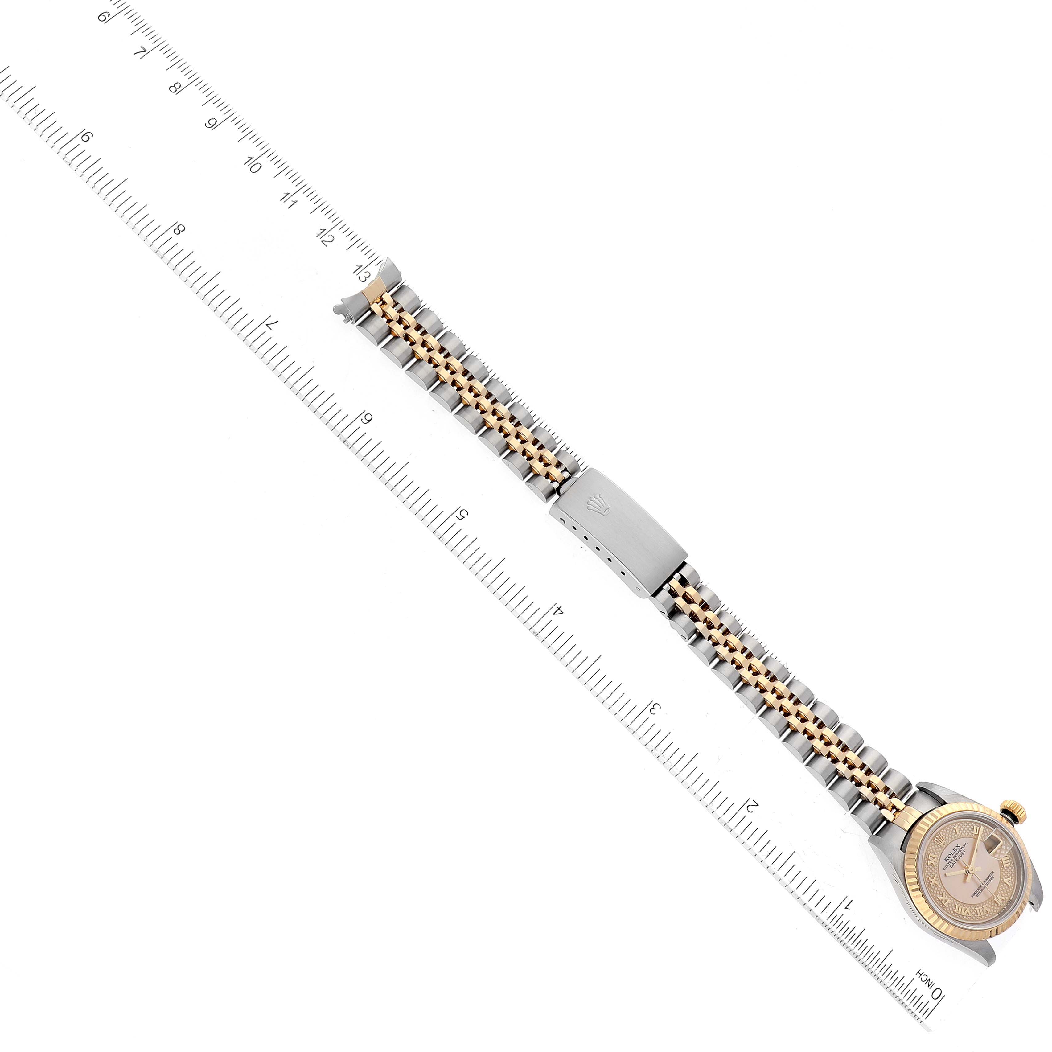The image shows a Rolex Datejust 79173 Women's Steel and Gold (two tone) Mother of Pearl Dial 79173 Women's Steel and Gold (two tone) Mother of Pearl Dial watch placed horizontally next to a ruler, revealing the band and crown from an aerial view.