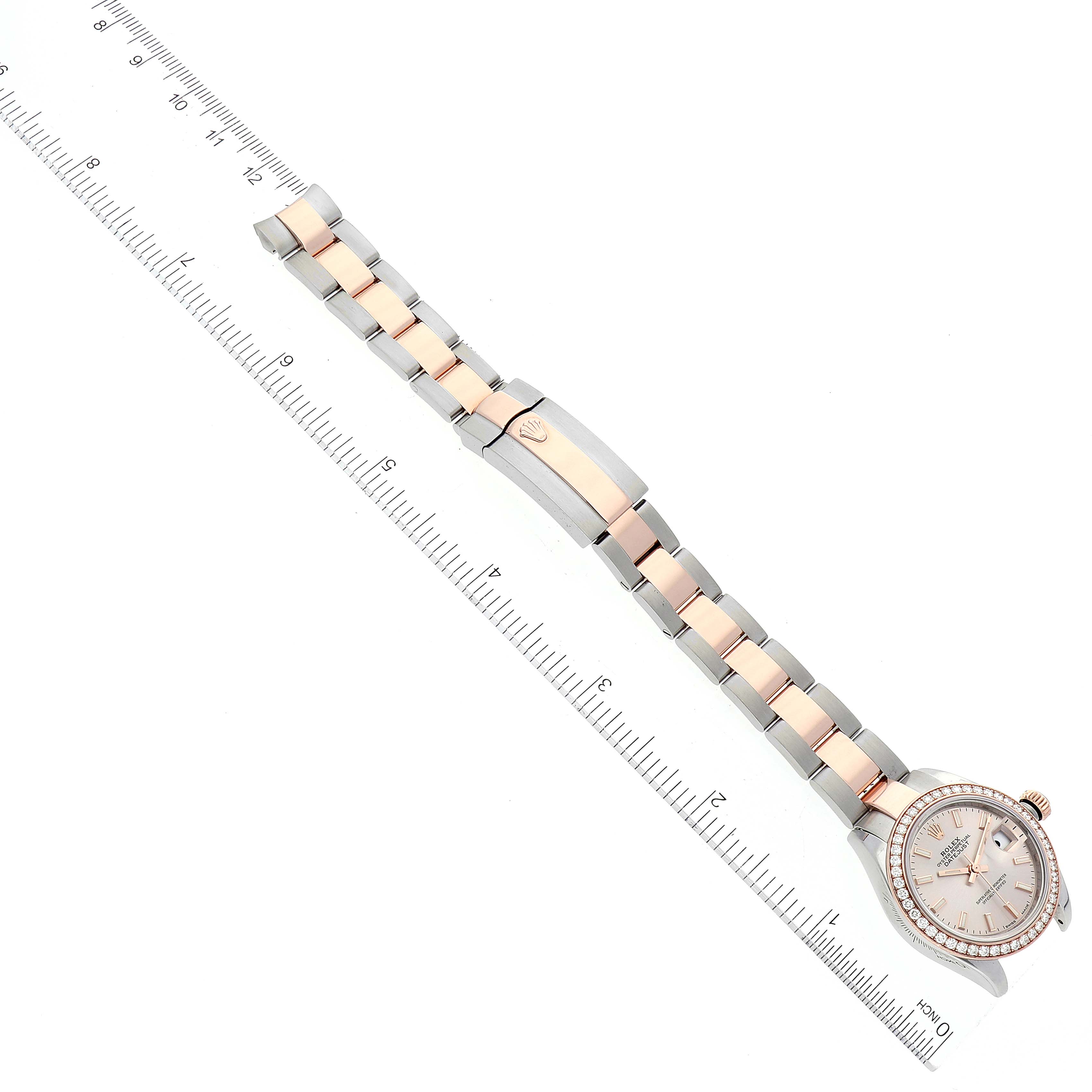 The image shows a Rolex Datejust 279381 Women's Steel and Gold (two tone) Pink Dial 279381 Women's Steel and Gold (two tone) Pink Dial watch laid flat against a ruler, displaying the face, bracelet, and clasp from an overhead angle.
