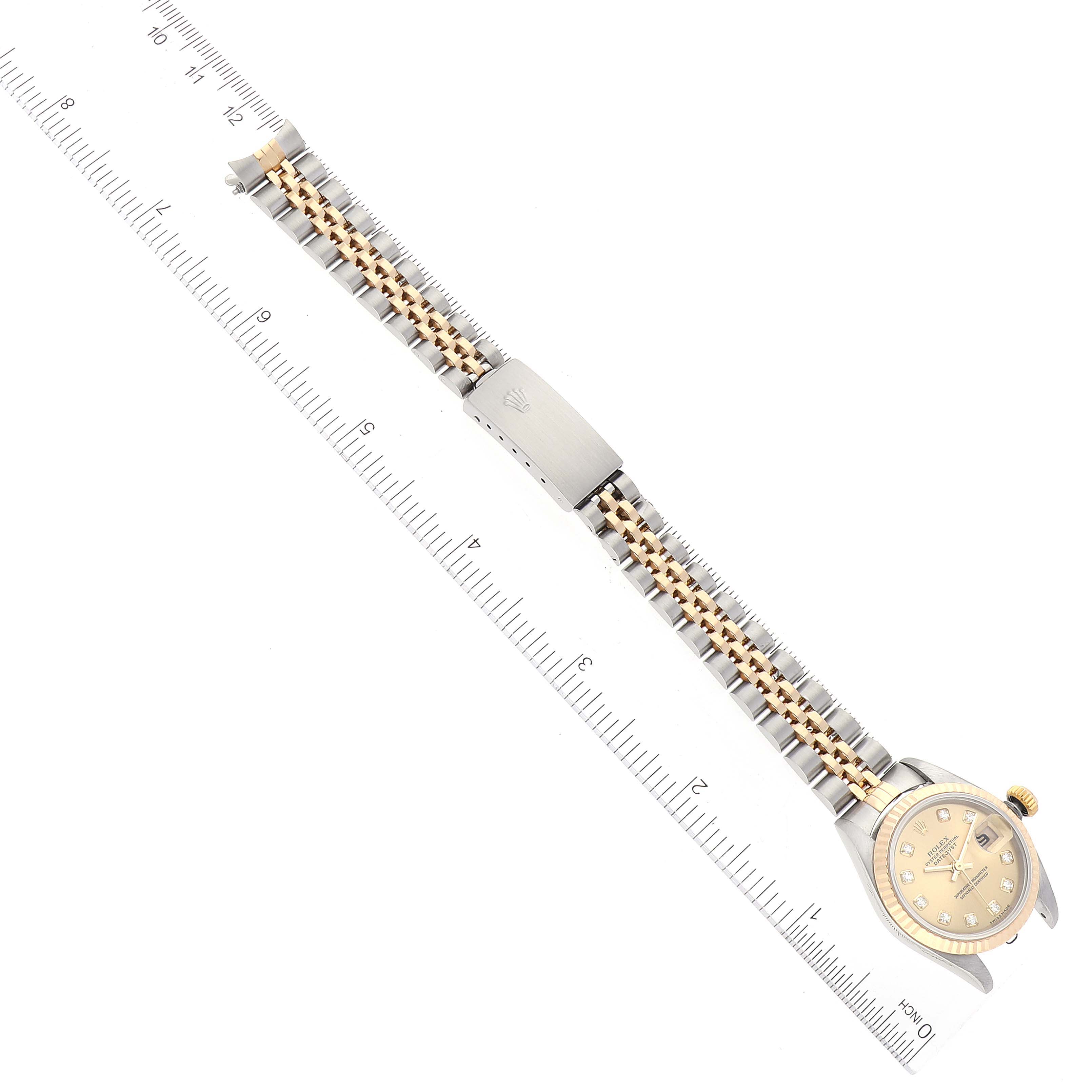 The image shows a Rolex Datejust 79173 Women's Steel and Gold (two tone) Champagne Dial 79173 Women's Steel and Gold (two tone) Champagne Dial watch laid flat, displaying the face, bracelet, and clasp next to a measuring ruler.