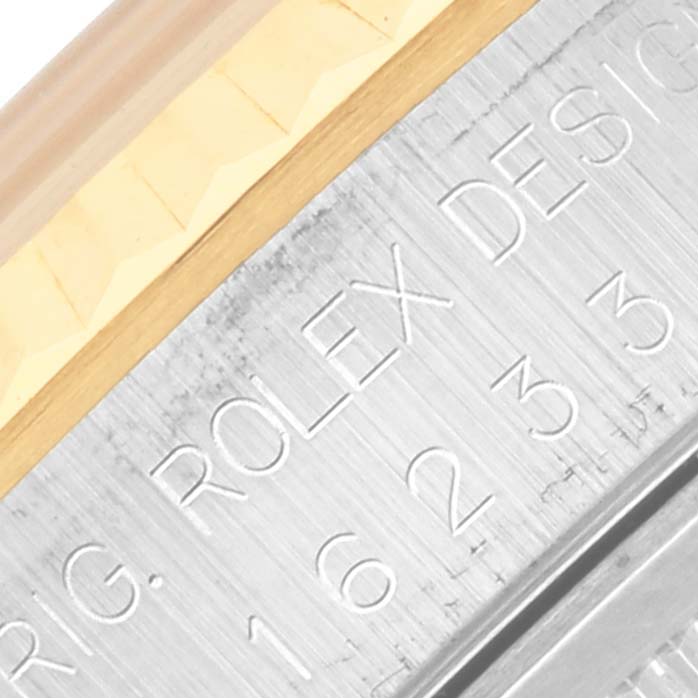 The image shows a close-up of the side of a Rolex Datejust 16233 Men's Steel and Gold (two tone) White Dial 16233 Men's Steel and Gold (two tone) White Dial, featuring the serial engraving and part of the fluted bezel.