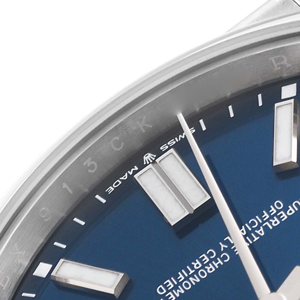 The image shows a close-up of the top right part of a blue dial of a Rolex Oyster Perpetual 124300 Men
s Stainless Steel Blue Dial 124300 Men
s Stainless Steel Blue Dial watch, focusing on the hands and indices.