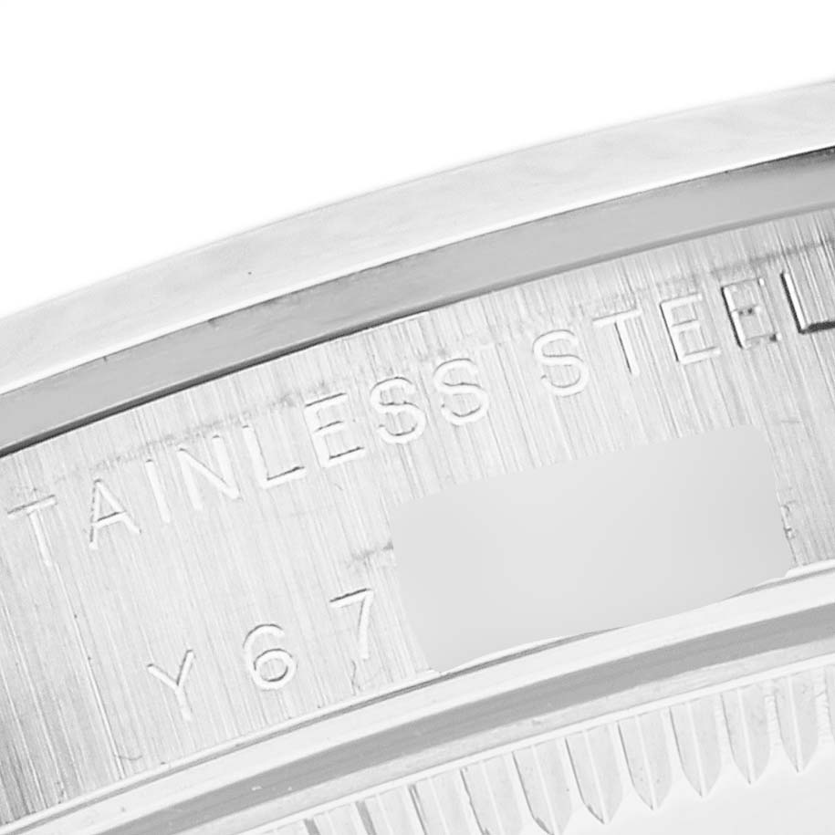This image shows an angled view of the stainless steel case back of a Mid-Size Rolex watch, displaying part of its engraved text.