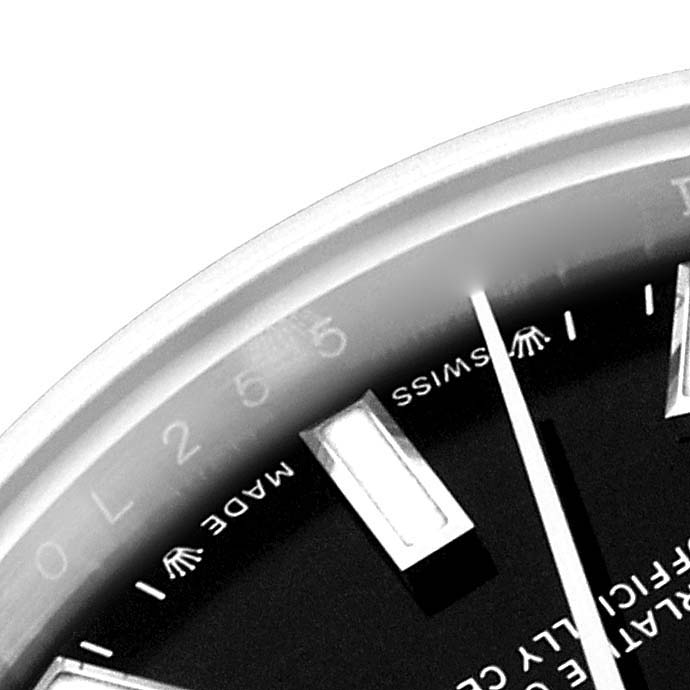 This close-up image of a Rolex Oyster Perpetual 276200 Women's Stainless Steel Black Dial 276200 Women's Stainless Steel Black Dial watch shows part of the dial, bezel, and hour markers.