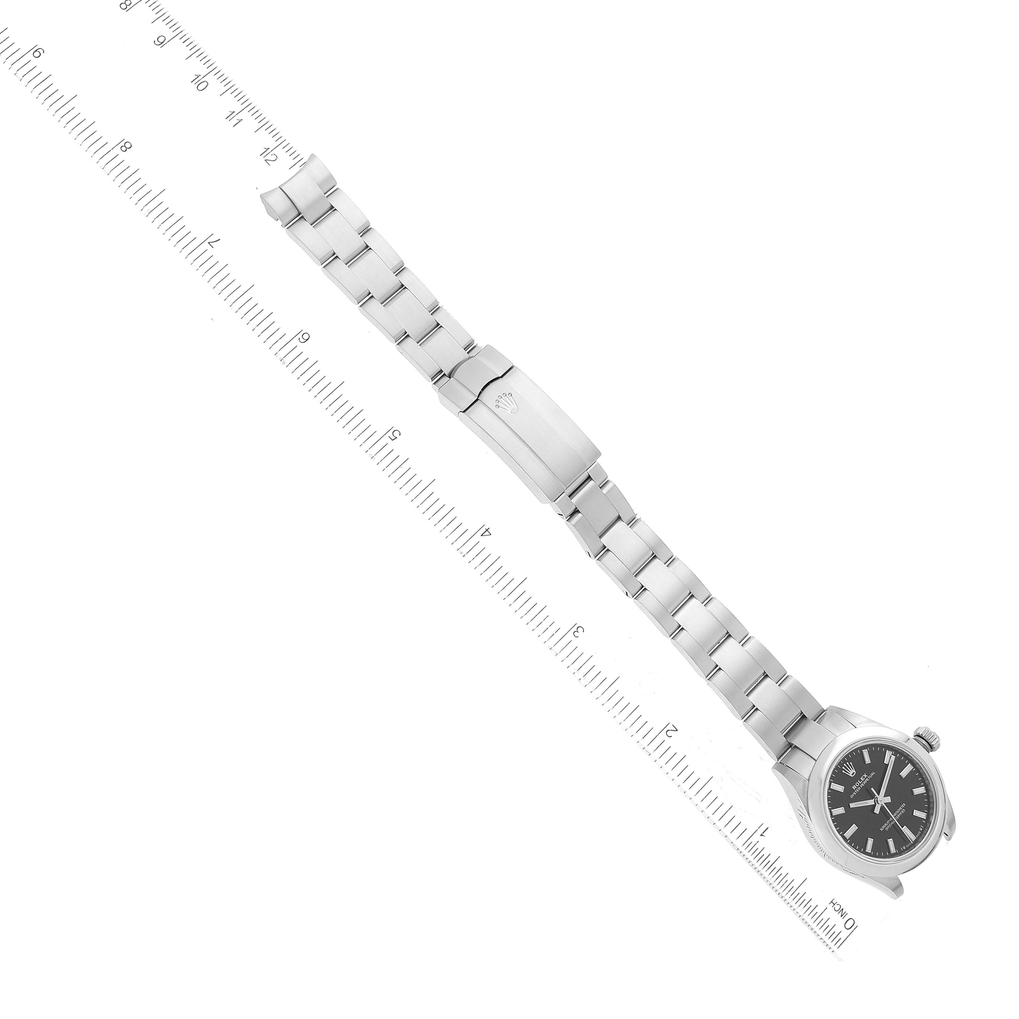 This image shows a top-down view of the Rolex Oyster Perpetual 276200 Women's Stainless Steel Black Dial 276200 Women's Stainless Steel Black Dial watch, including its dial, bracelet, and clasp, alongside a ruler for scale.