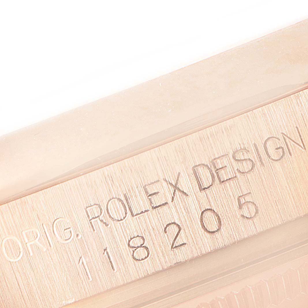 The image shows a close-up of the model and serial number engraving on a Rolex President 118205 Men's Rose Gold Silver Dial 118205 Men's Rose Gold Silver Dial watch.