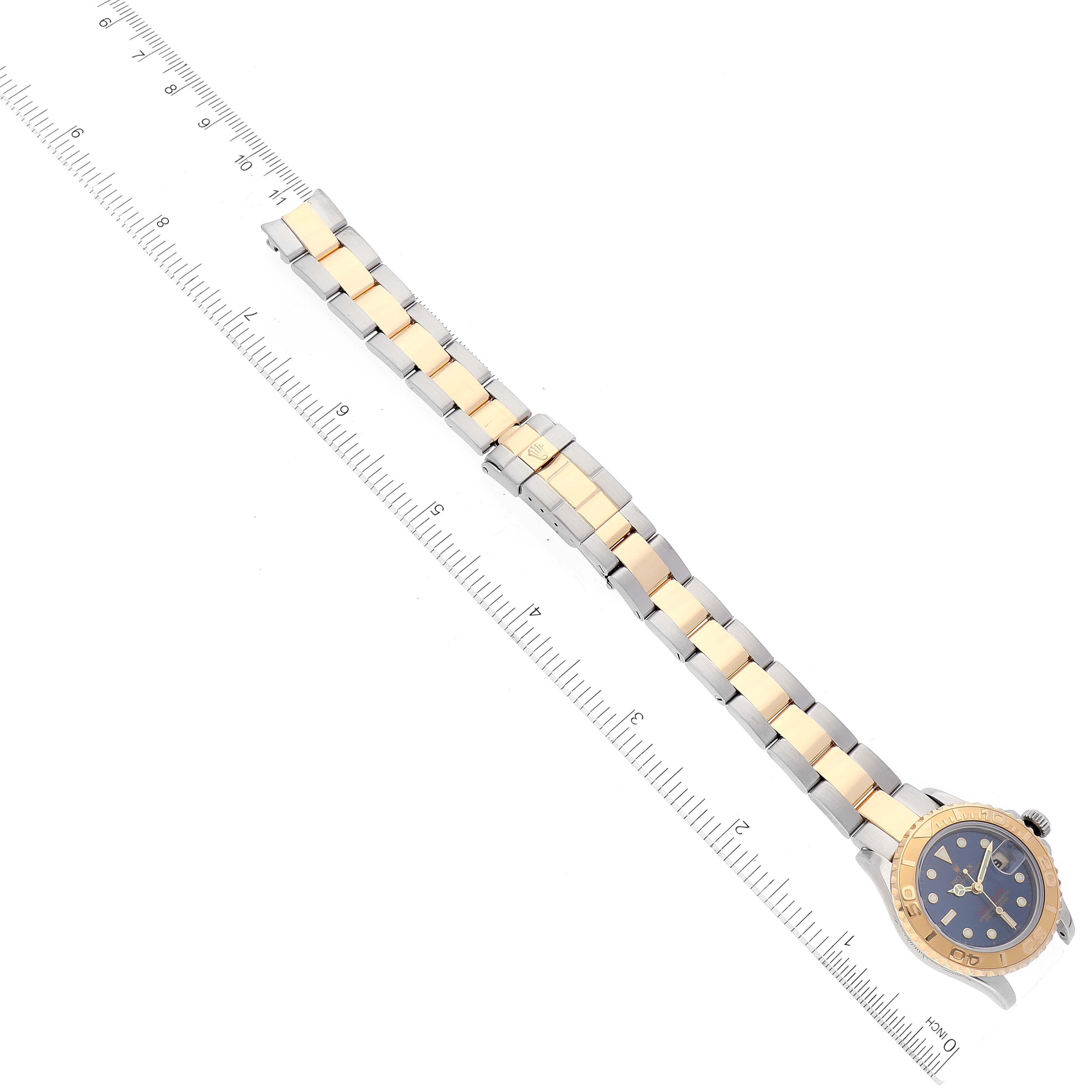 This image shows a top view of the Rolex Yacht-Master 169623 Women's Steel and Gold (two tone) Blue Dial 169623 Women's Steel and Gold (two tone) Blue Dial watch, highlighting its bracelet, bezel, and dial, with a ruler for scale.