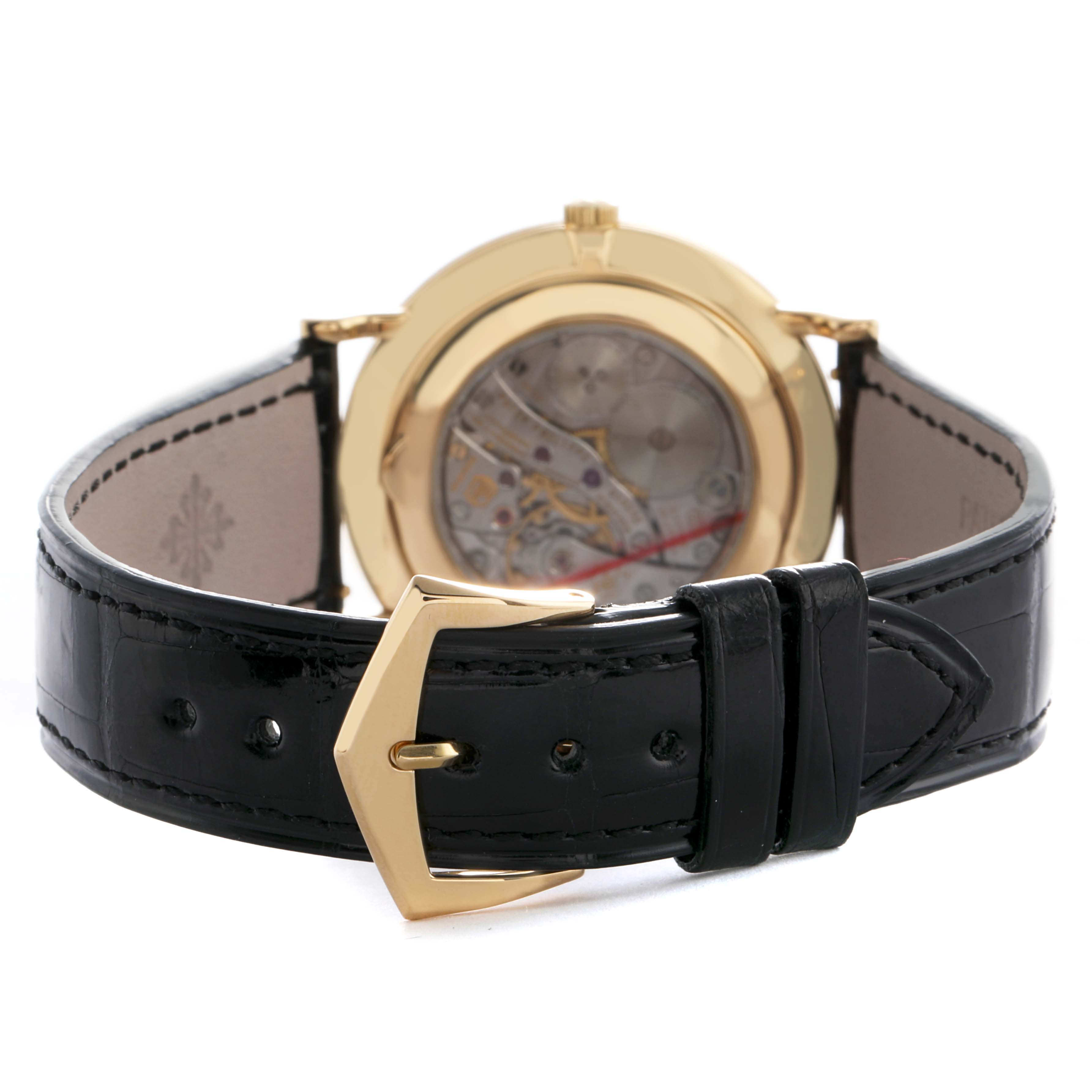 The image shows the back view of a Patek Philippe Calatrava 5119J-001 Men's Yellow Gold White Dial watch, highlighting the leather strap, buckle, and transparent case back.