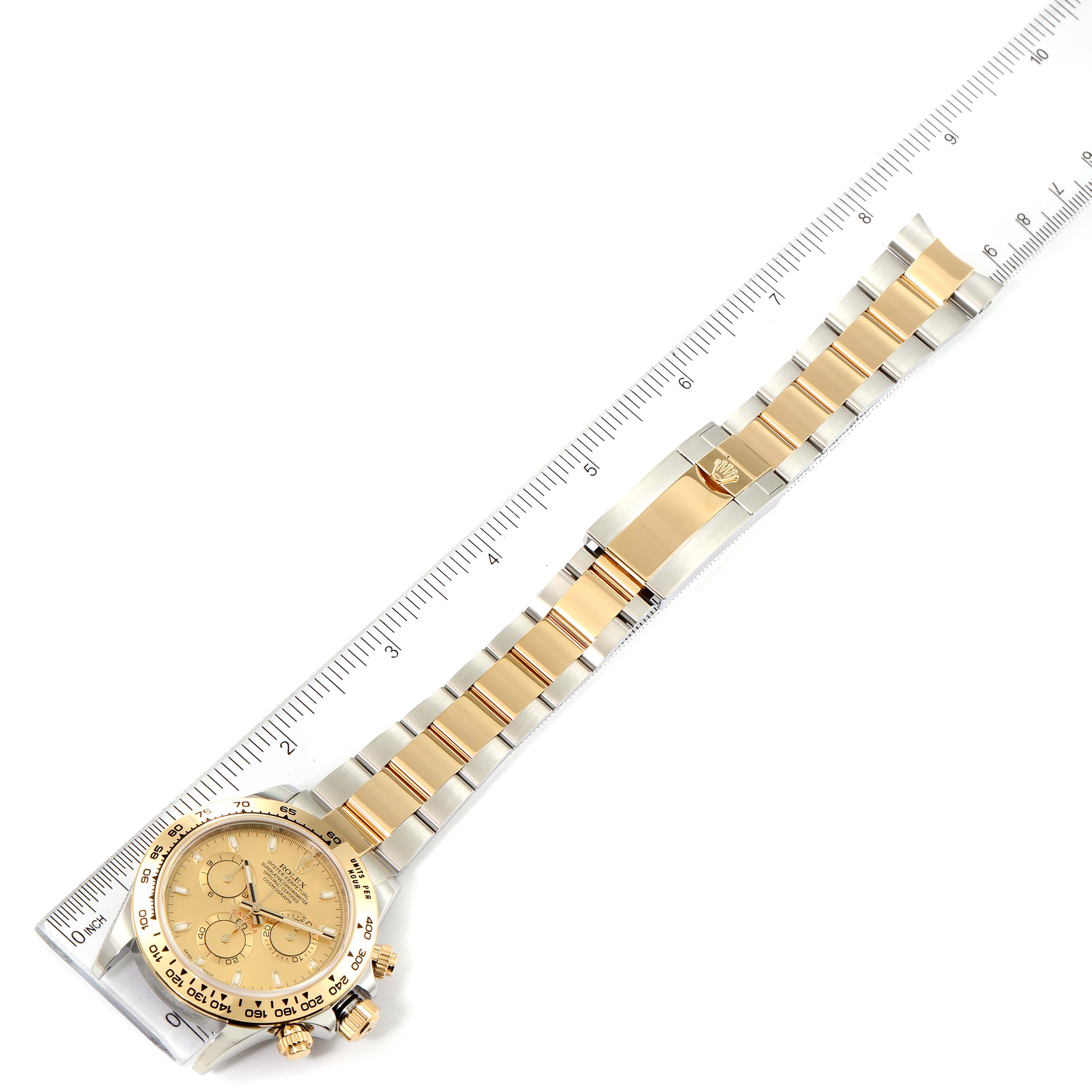 The image shows a Rolex Daytona 116503 Men
s Steel and Gold (two tone) Champagne Dial 116503 Men
s Steel and Gold (two tone) Champagne Dial watch laid flat, highlighting the watch face and two-tone bracelet against a ruler.
