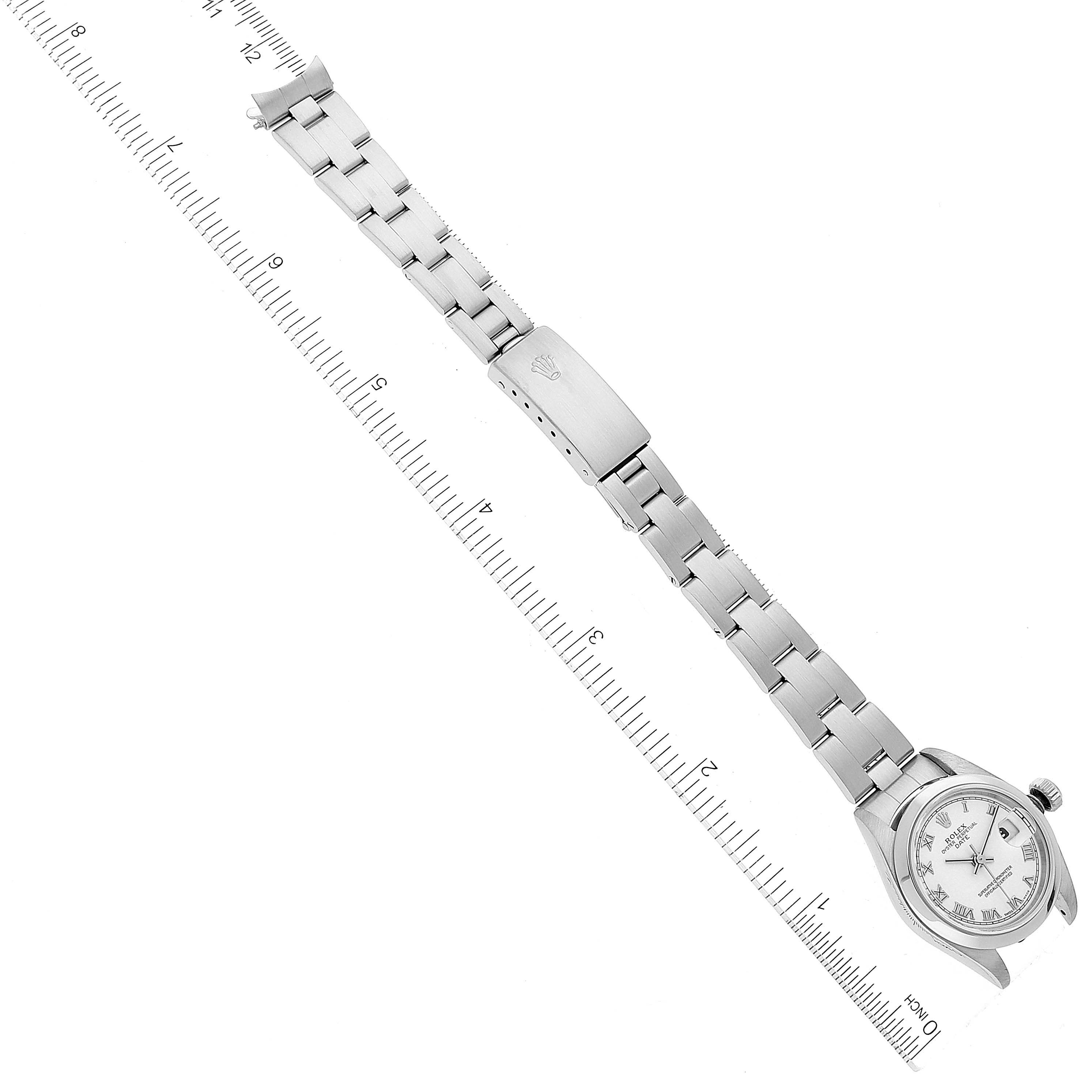 The image shows a full view of a Rolex Date 79160 Women's Stainless Steel White Dial 79160 Women's Stainless Steel White Dial model watch, laid flat with the clasp and bracelet fully extended next to a ruler.