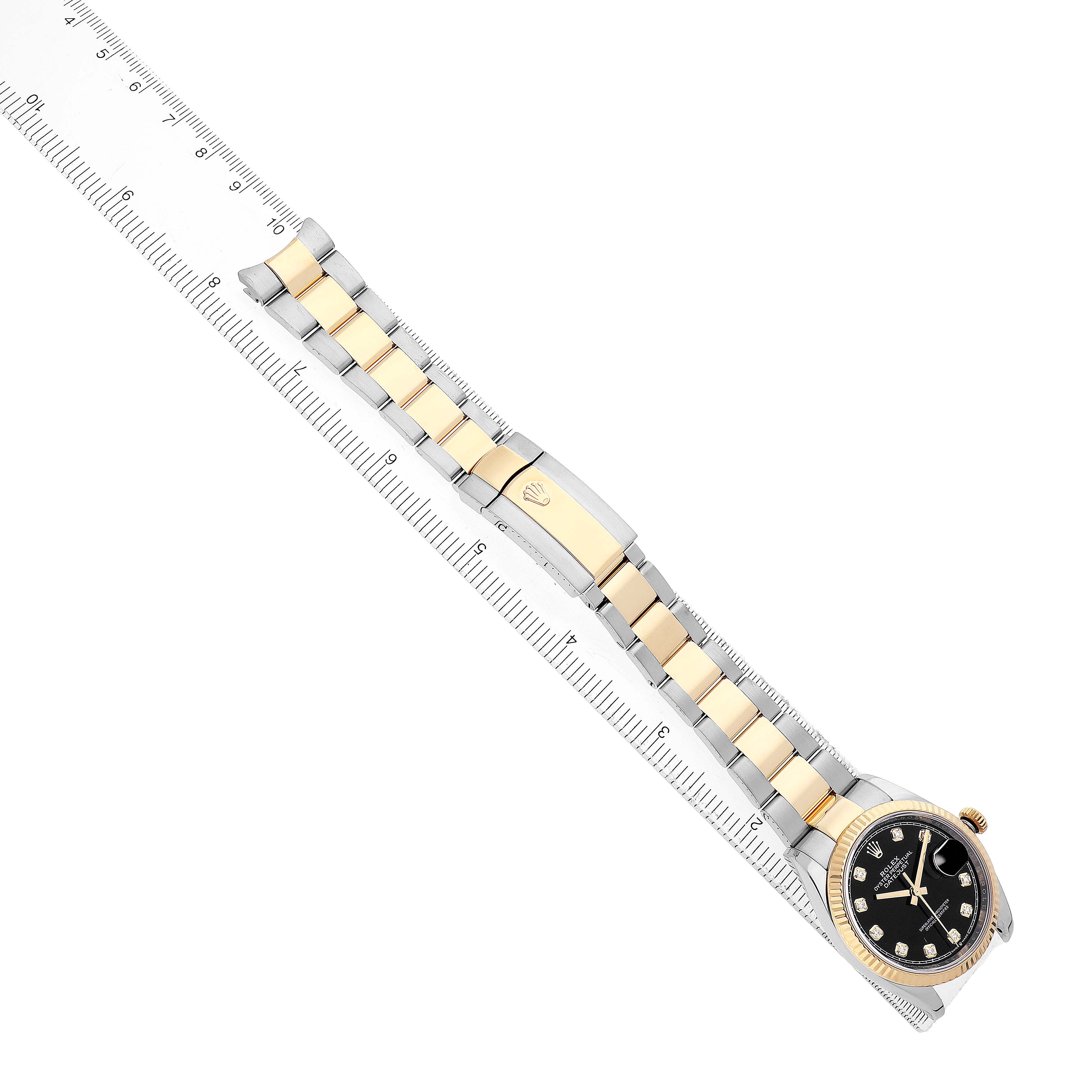 The Rolex Datejust 126233 Men's Steel and Gold (two tone) Black Dial watch is shown from a top view, displaying its entire bracelet, clasp, and watch face alongside a ruler.