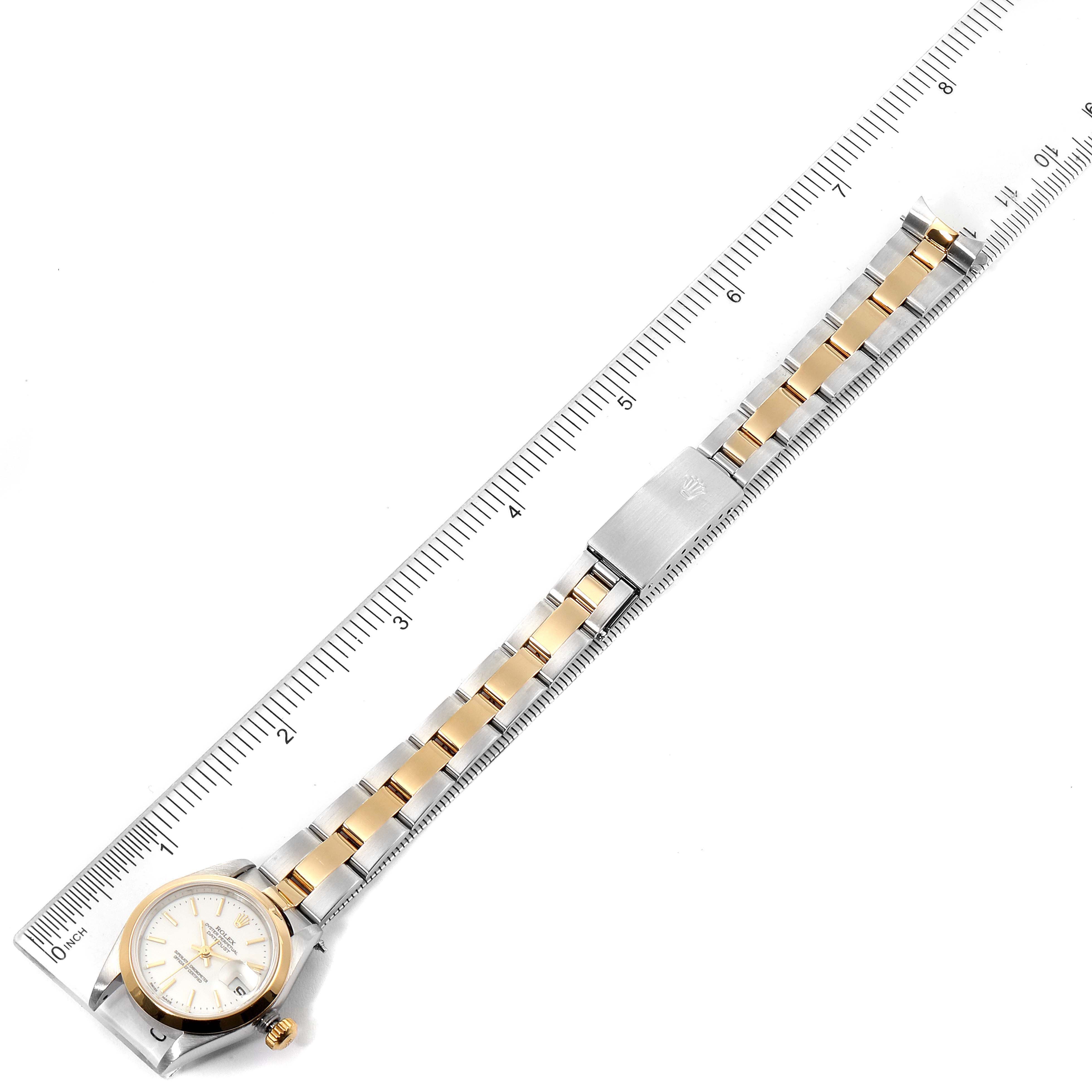 The Rolex Datejust 79163 Women's Steel and Gold (two tone) White Dial 79163 Women's Steel and Gold (two tone) White Dial watch is shown from a top-down angle, displaying its face, bracelet, and clasp alongside a ruler.