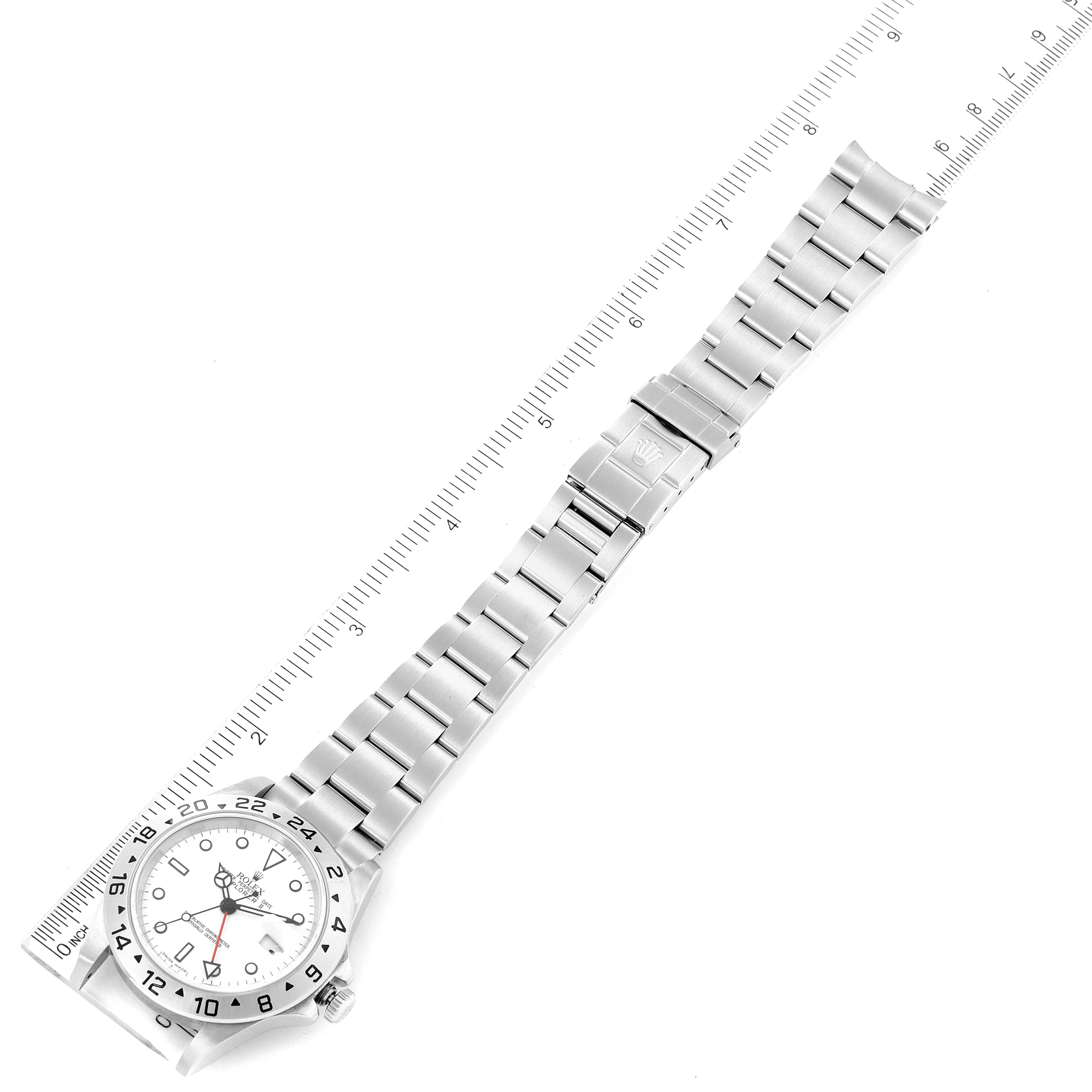 The image shows a top-down view of a Rolex Explorer 16570 Men
s Stainless Steel White Dial 16570 Men
s Stainless Steel White Dial watch laying next to a ruler.