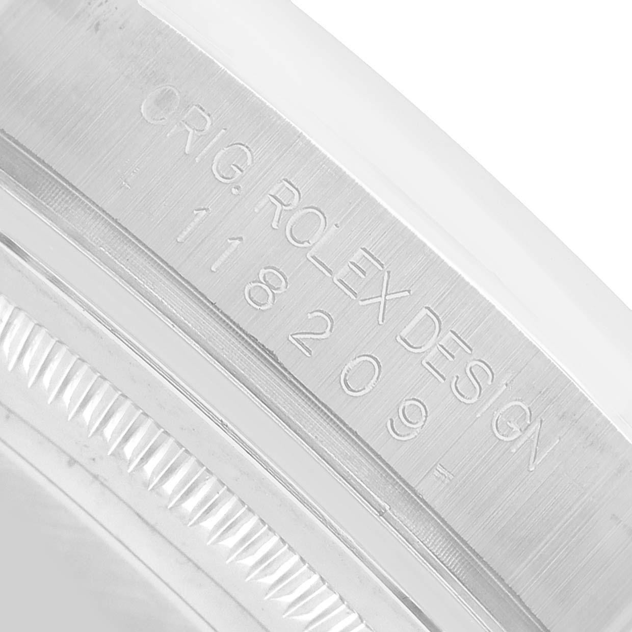 The image shows a close-up of the engravings on the case of a Rolex President 118209 Men's White Gold Silver Dial model watch.