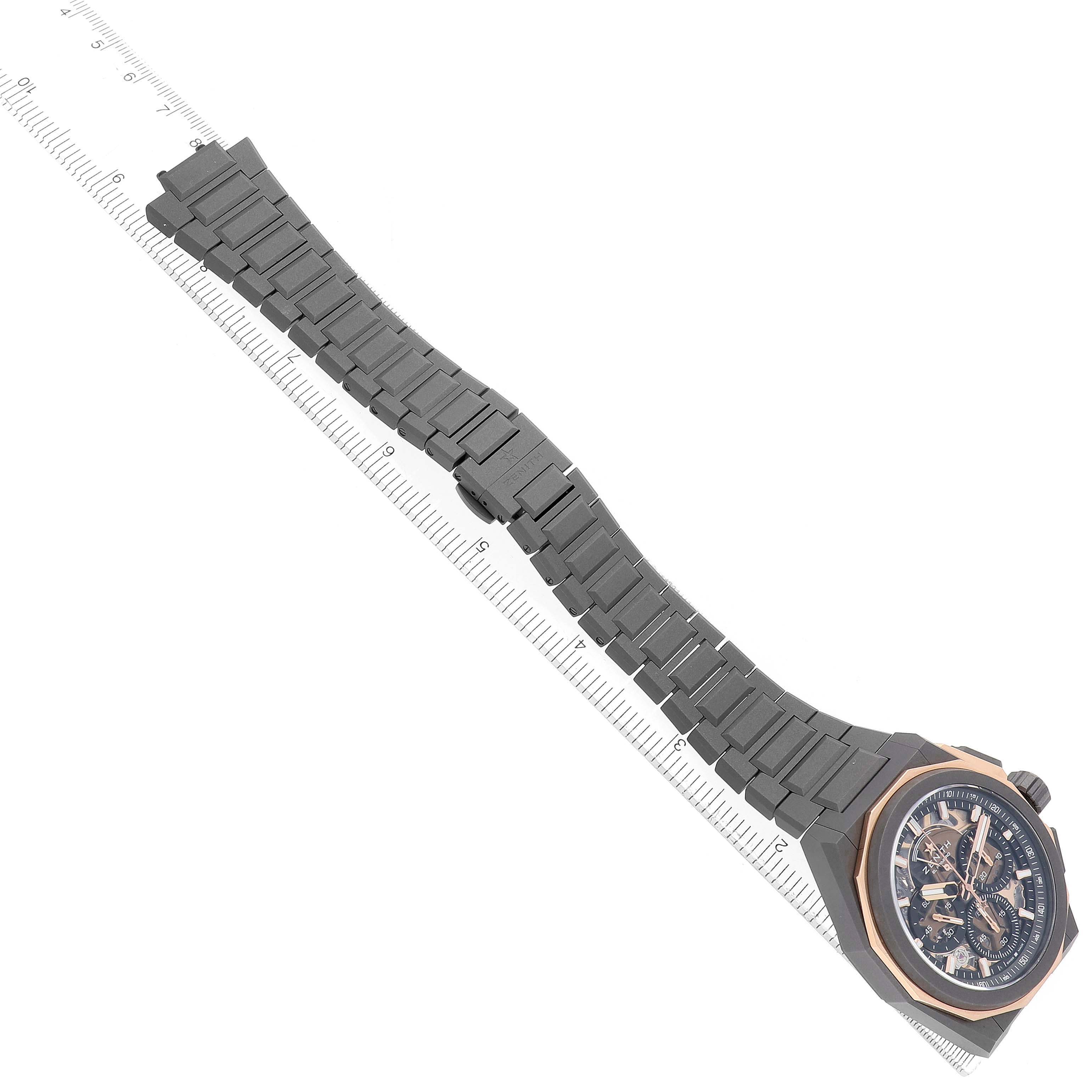 The Zenith Defy 87.9100.9004/03.I001 Men's Titanium Grey Dial watch is shown diagonally with the full bracelet and the face visible, positioned next to a ruler.