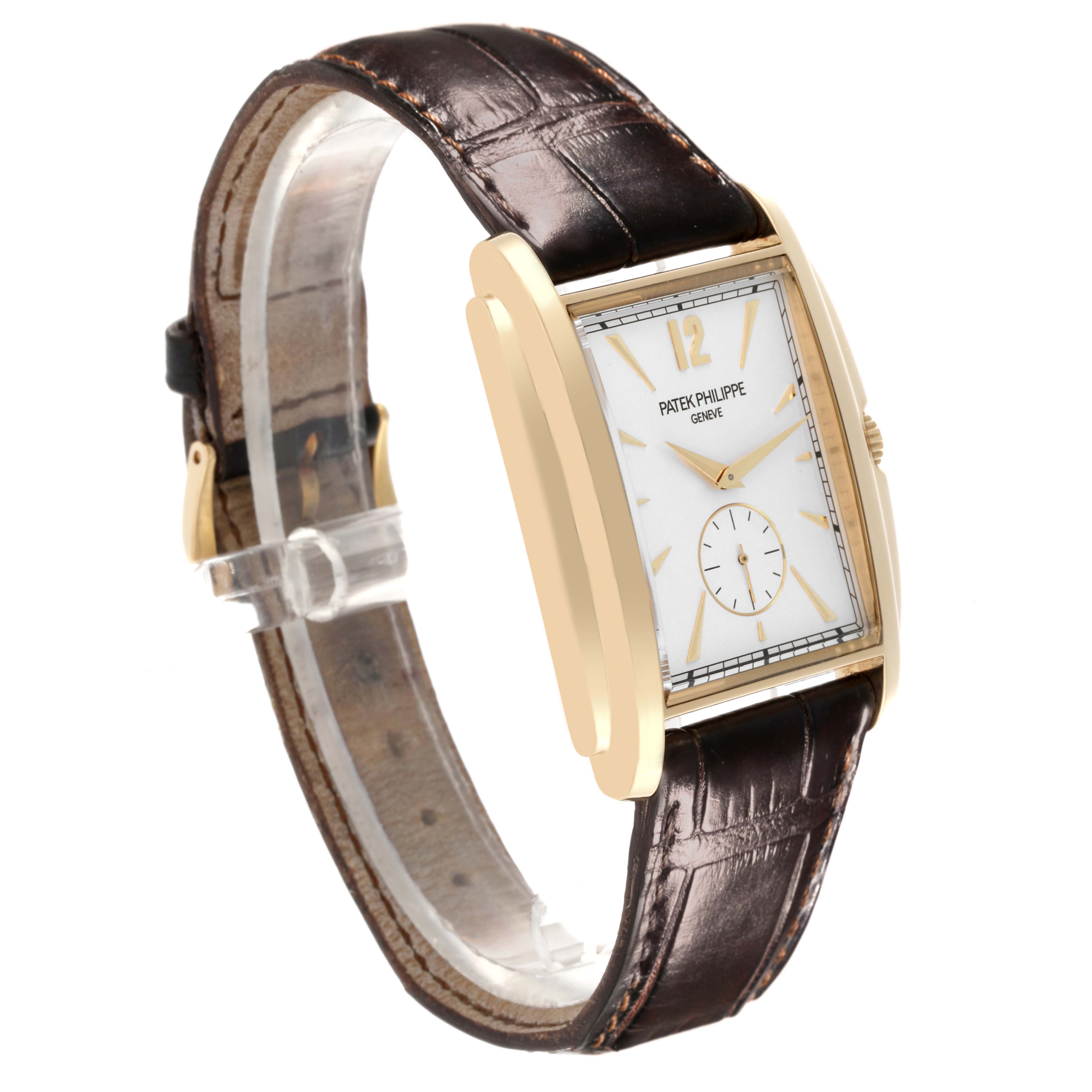 The Patek Philippe Gondolo 5124J Men's Yellow Gold Silver Dial 5124J Men's Yellow Gold Silver Dial watch is shown at a slight side angle, highlighting its rectangular face, gold casing, and leather strap.