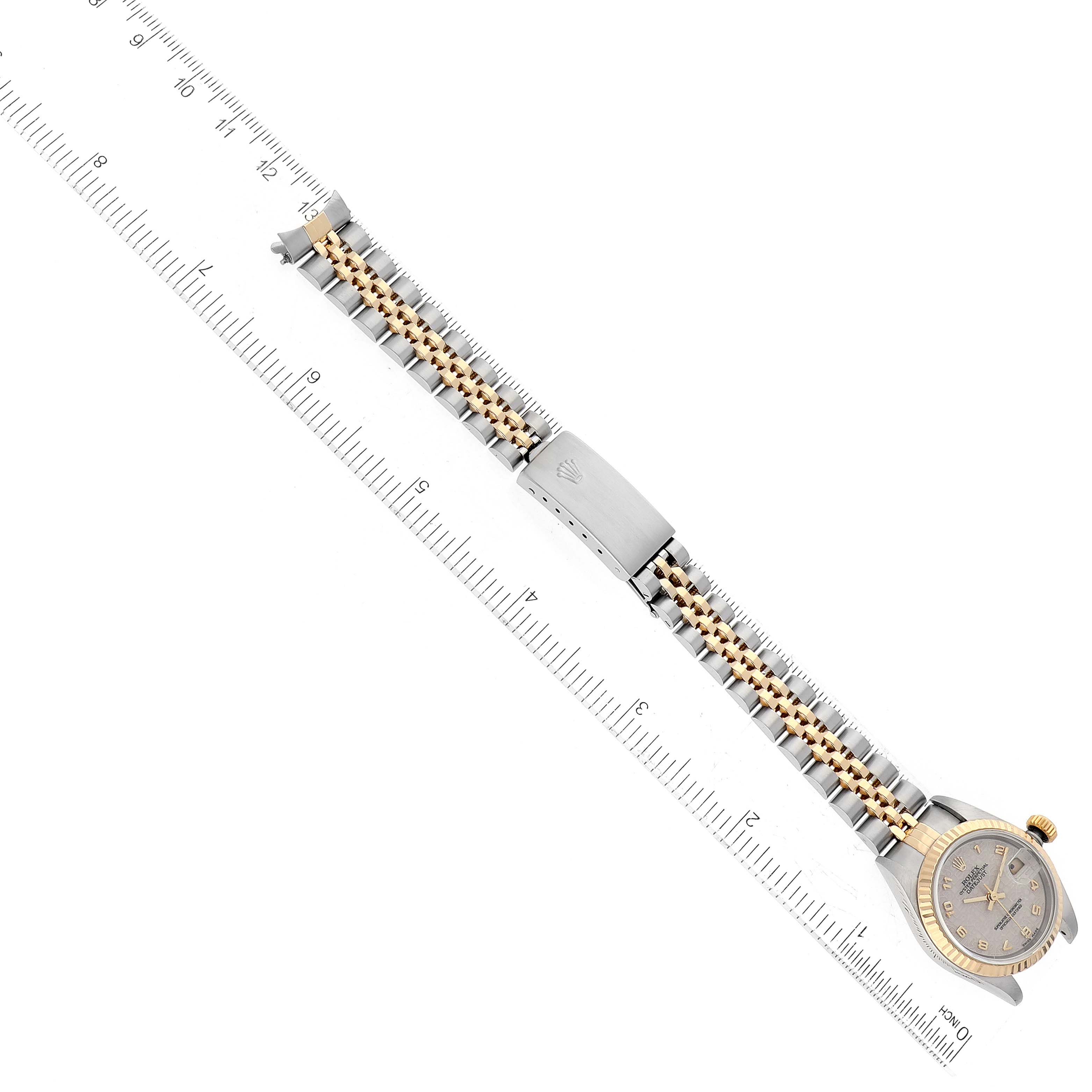 The image shows a top view of a Rolex Datejust 79173 Women's Steel and Gold (two tone) White Dial 79173 Women's Steel and Gold (two tone) White Dial watch, showcasing the face, bezel, and metal bracelet along with a ruler for scale.