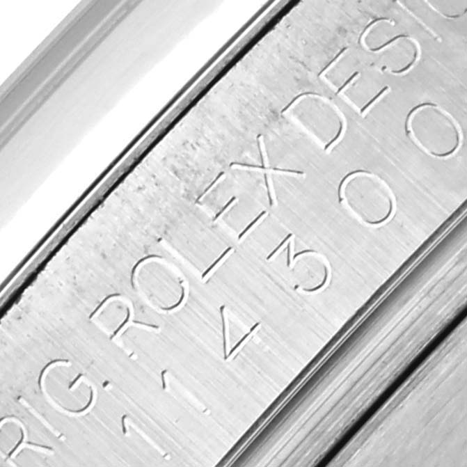 The image shows a close-up of the engraving on the inner bezel of a Rolex Oyster Perpetual 114300 Men's Stainless Steel Silver Dial 114300 Men's Stainless Steel Silver Dial watch.