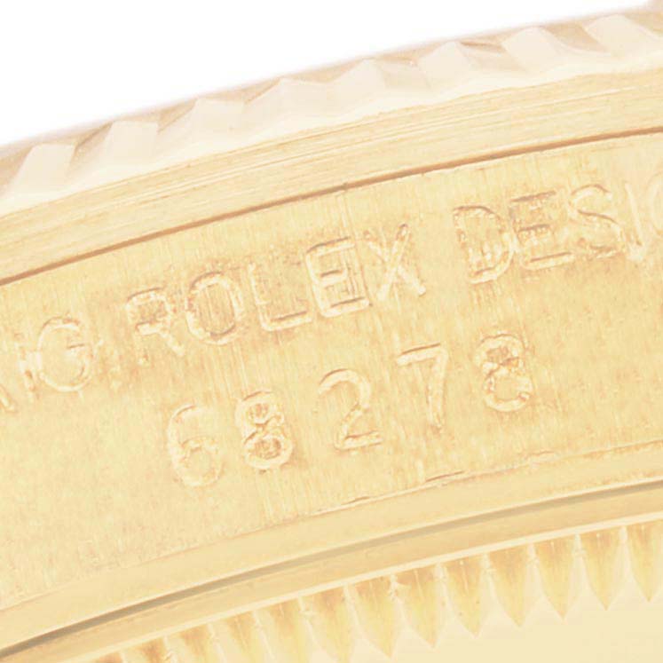 This close-up image shows the engraved serial number and part of the fluted bezel on a Rolex President 68278G Women's Yellow Gold Champagne Dial 68278G Women's Yellow Gold Champagne Dial model.