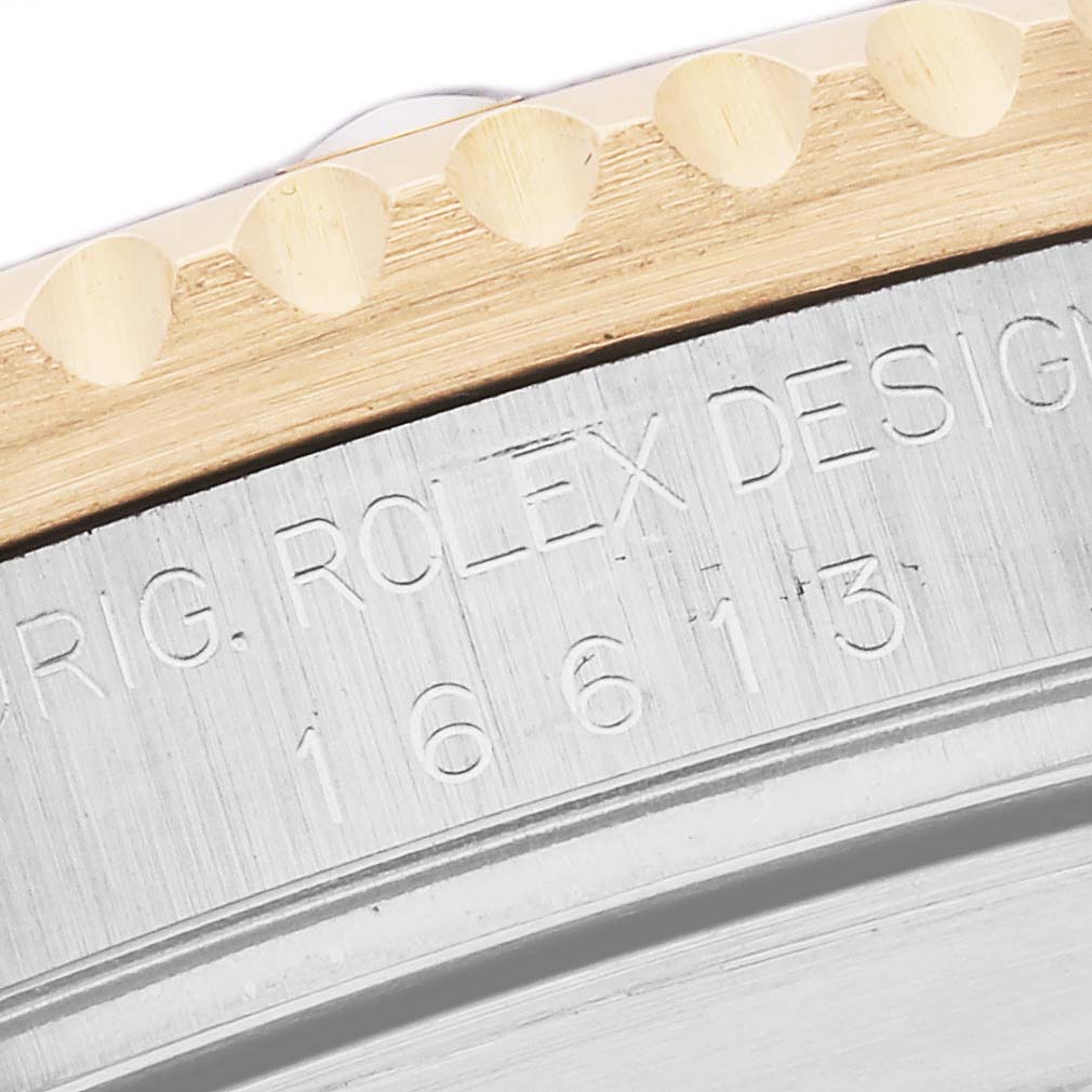 The image shows a close-up of the Rolex Submariner 16613 Men's Steel and Gold (two tone) Blue Dial 16613 Men's Steel and Gold (two tone) Blue Dial's bezel and case with engraved text.