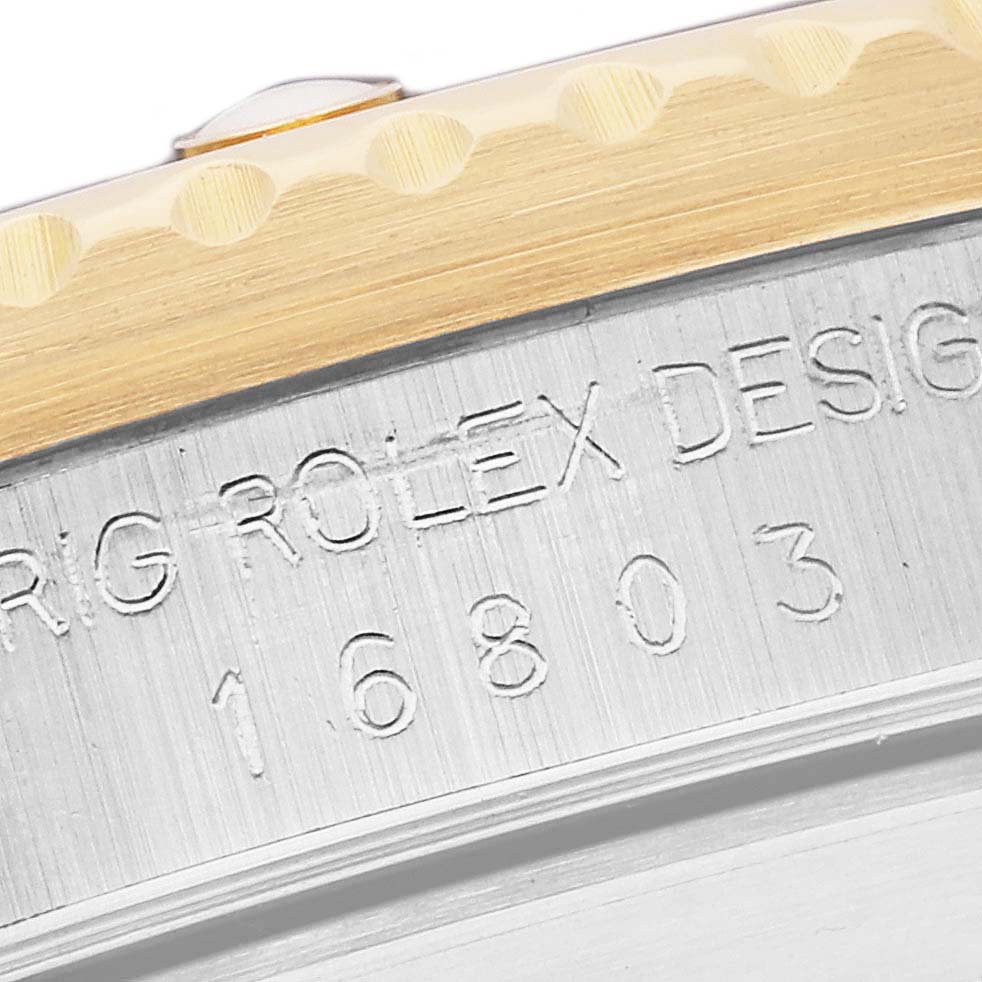 The image shows a close-up of the model number and part of the bezel of a Rolex Submariner 16803 Men's Steel and Gold (two tone) Blue Dial 16803 Men's Steel and Gold (two tone) Blue Dial.