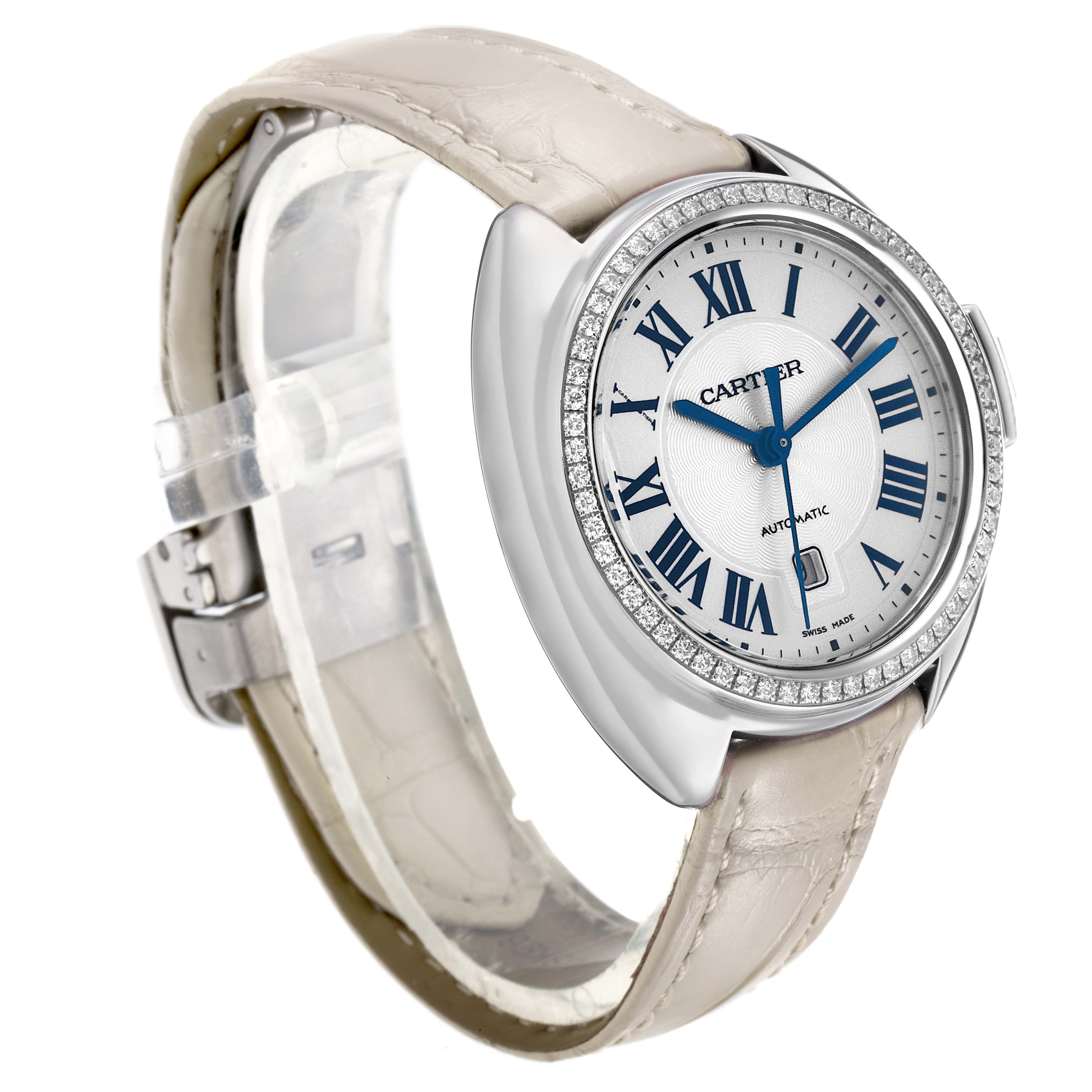 The Cartier Clé watch is shown at a three-quarter angle, highlighting the dial, bezel, and leather strap.