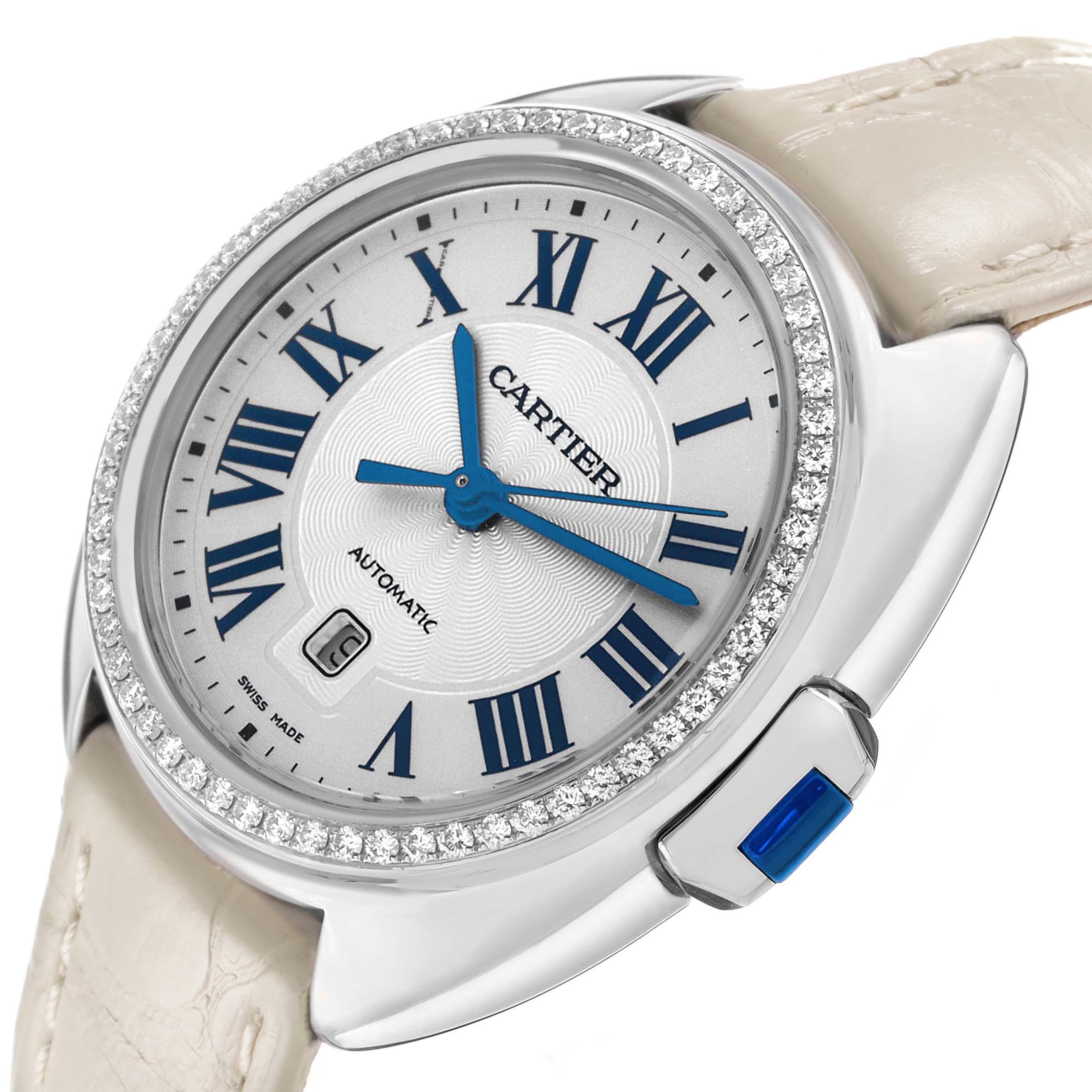 The Cartier Clé watch is shown at a slight angle, highlighting the diamond bezel, blue hands, and Roman numeral dial.