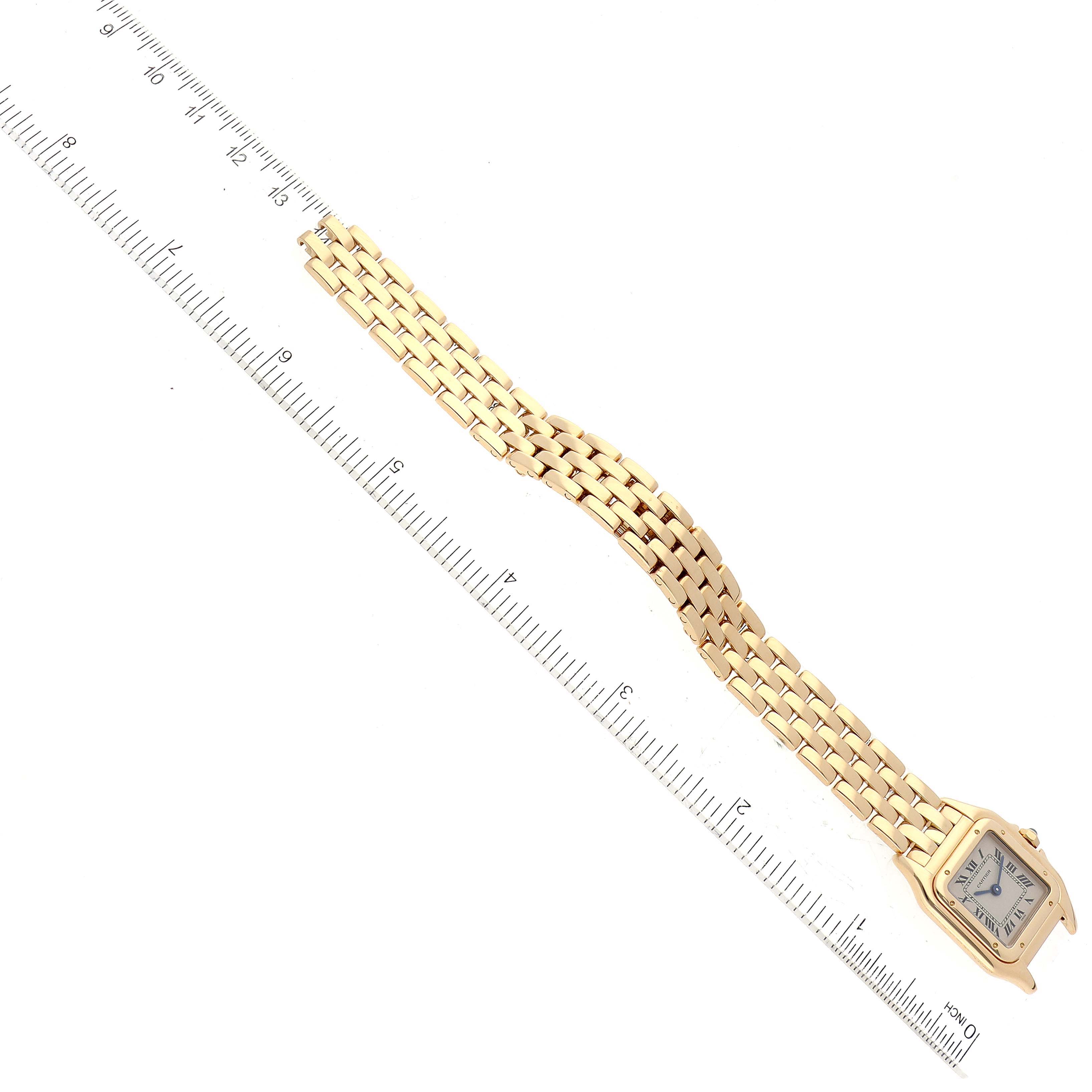The image shows a top-down view of a Cartier Panthere 107000M Women's Yellow Gold Silver Dial 107000M Women's Yellow Gold Silver Dial watch with its bracelet and part of a measuring ruler.