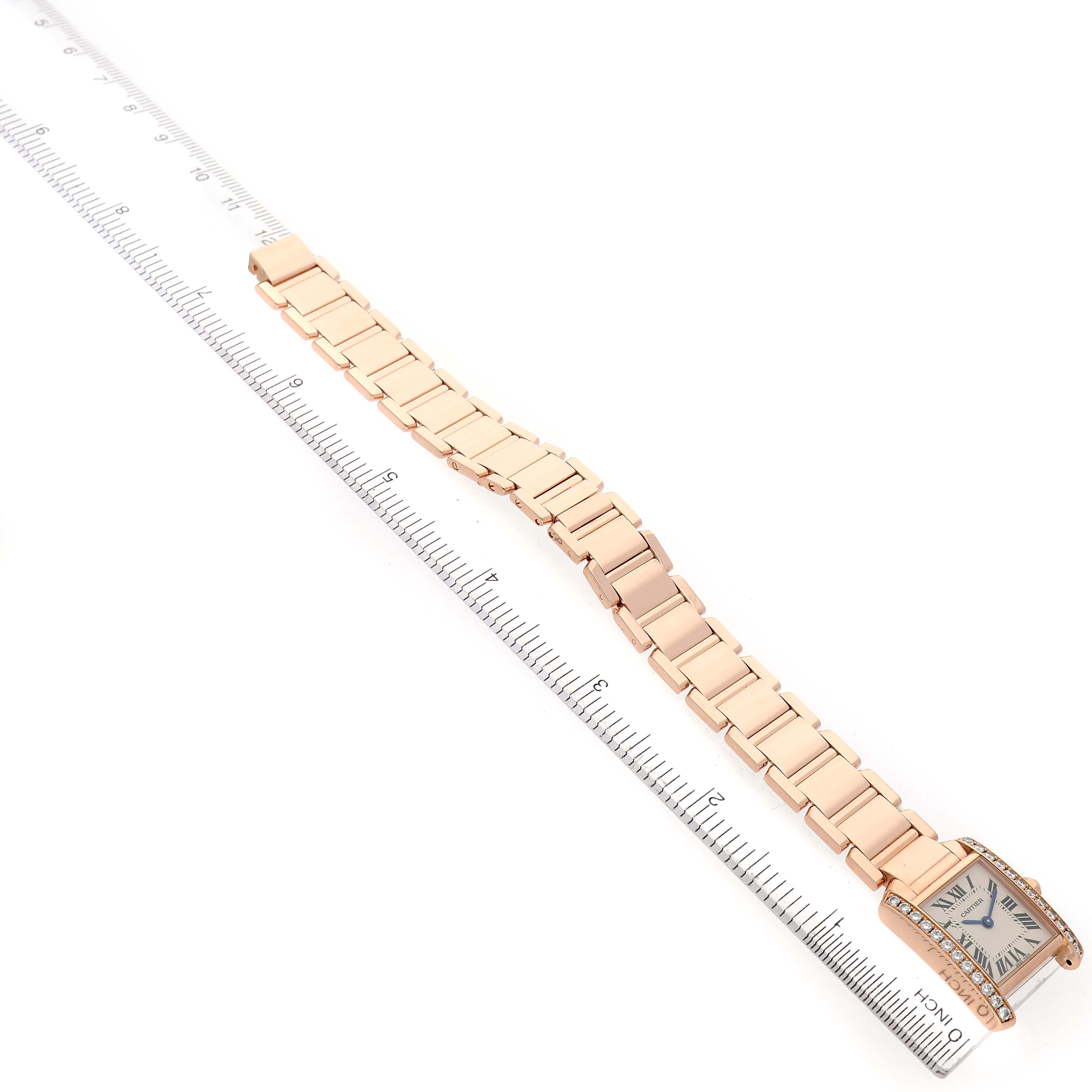 The Cartier Tank Française watch is shown from a top angle, displaying the face and full linked bracelet alongside a ruler for scale.