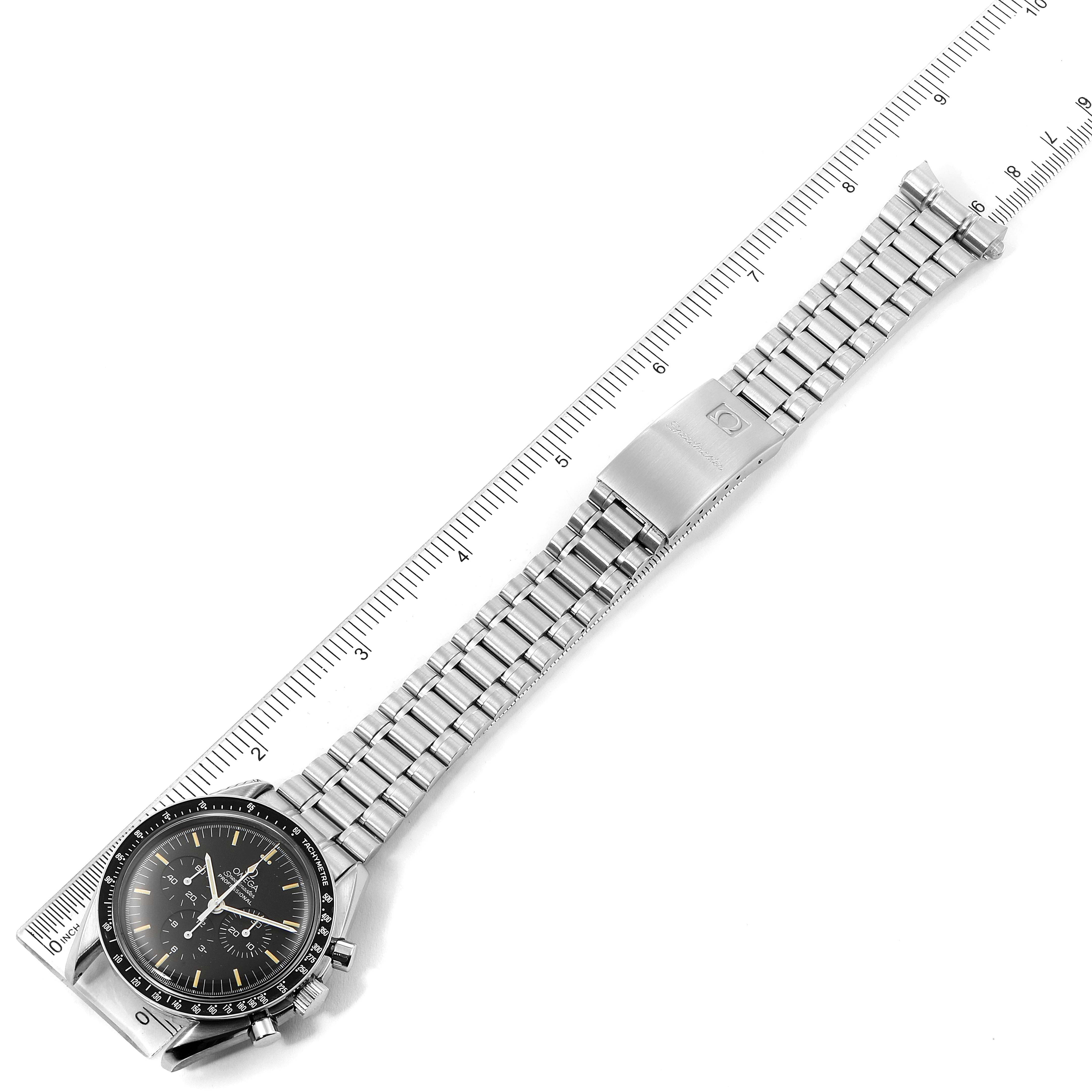 The Omega Speedmaster 3590.50.00 Men
s Stainless Steel Black Dial 3590.50.00 Men
s Stainless Steel Black Dial watch is shown diagonally from above, displaying its face, metal bracelet, and clasp alongside a ruler.