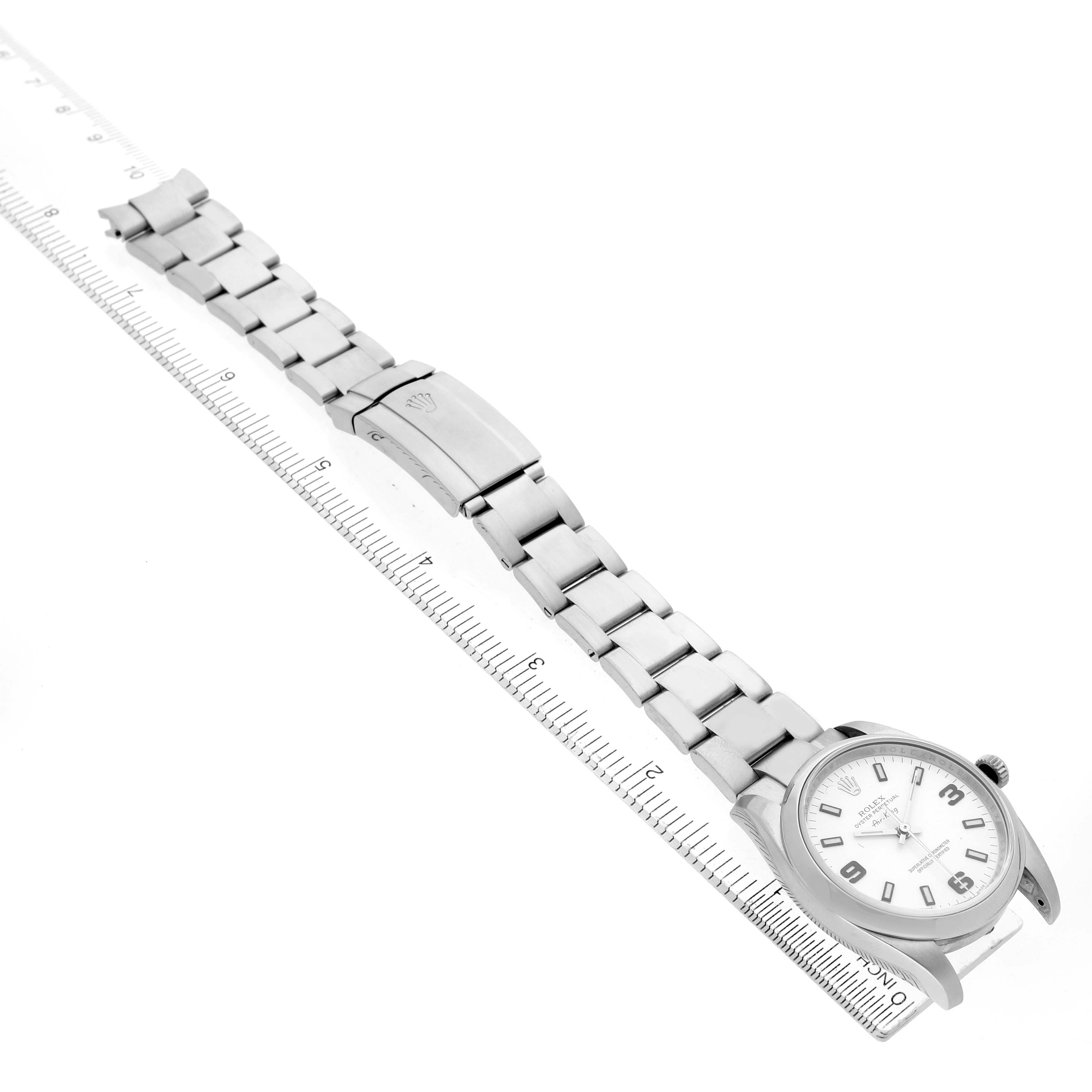 The Rolex Air-King 114200 Men's Stainless Steel White Dial watch is shown from a top view, featuring its face, bracelet, and clasp alongside a ruler.