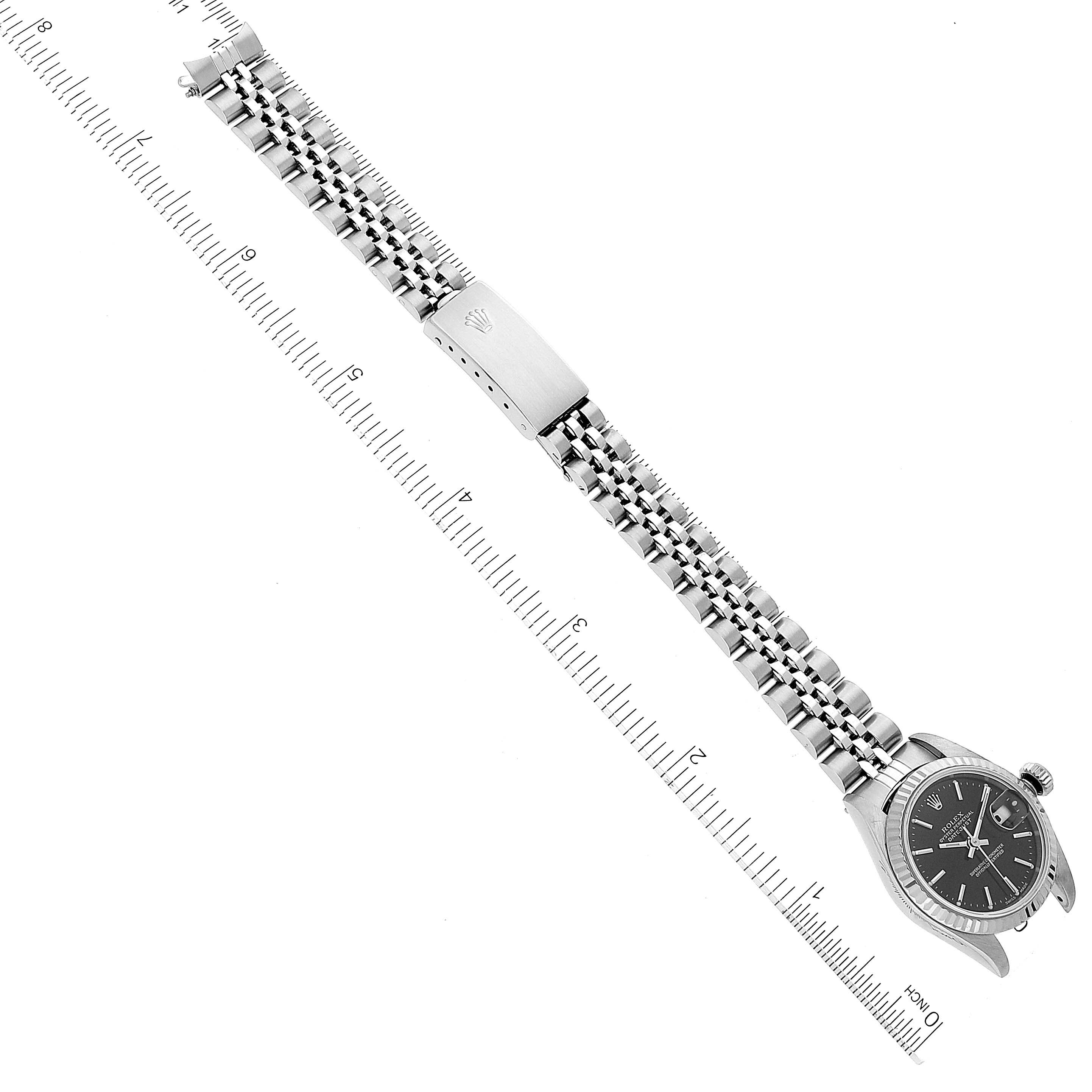 The image shows a Rolex Datejust 79174 Women's Stainless Steel Black Dial 79174 Women's Stainless Steel Black Dial watch placed horizontally, fully displaying the face, bracelet, and clasp, with a ruler for scale.