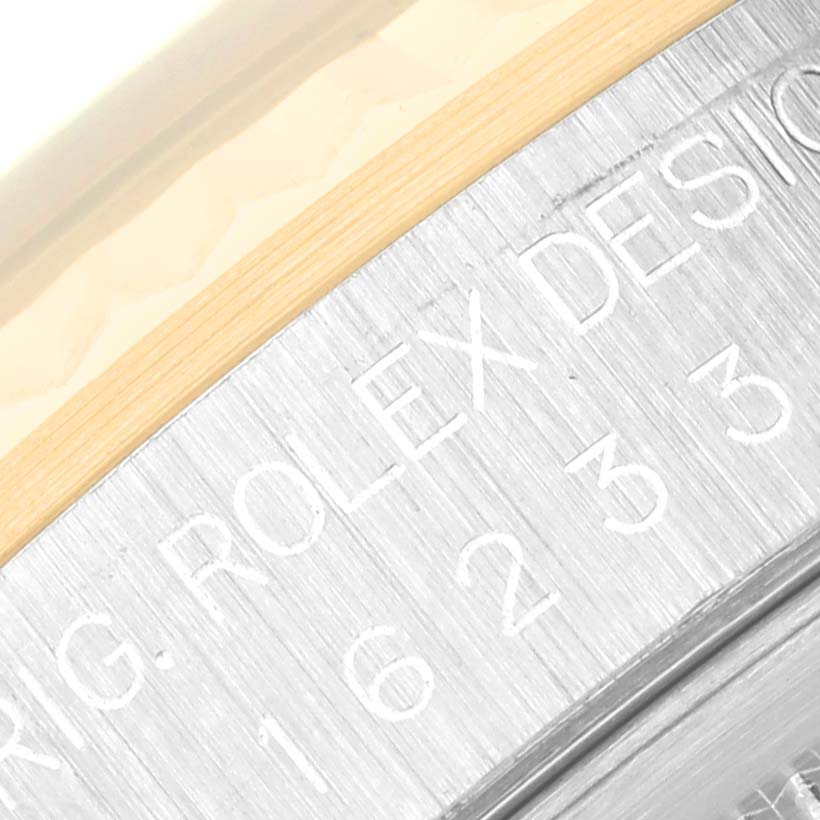 The image shows an angled close-up of the engraved bezel of a Rolex Datejust 16233 Men's Steel and Gold (two tone) Black Dial 16233 Men's Steel and Gold (two tone) Black Dial watch, highlighting the Rolex Design markings.
