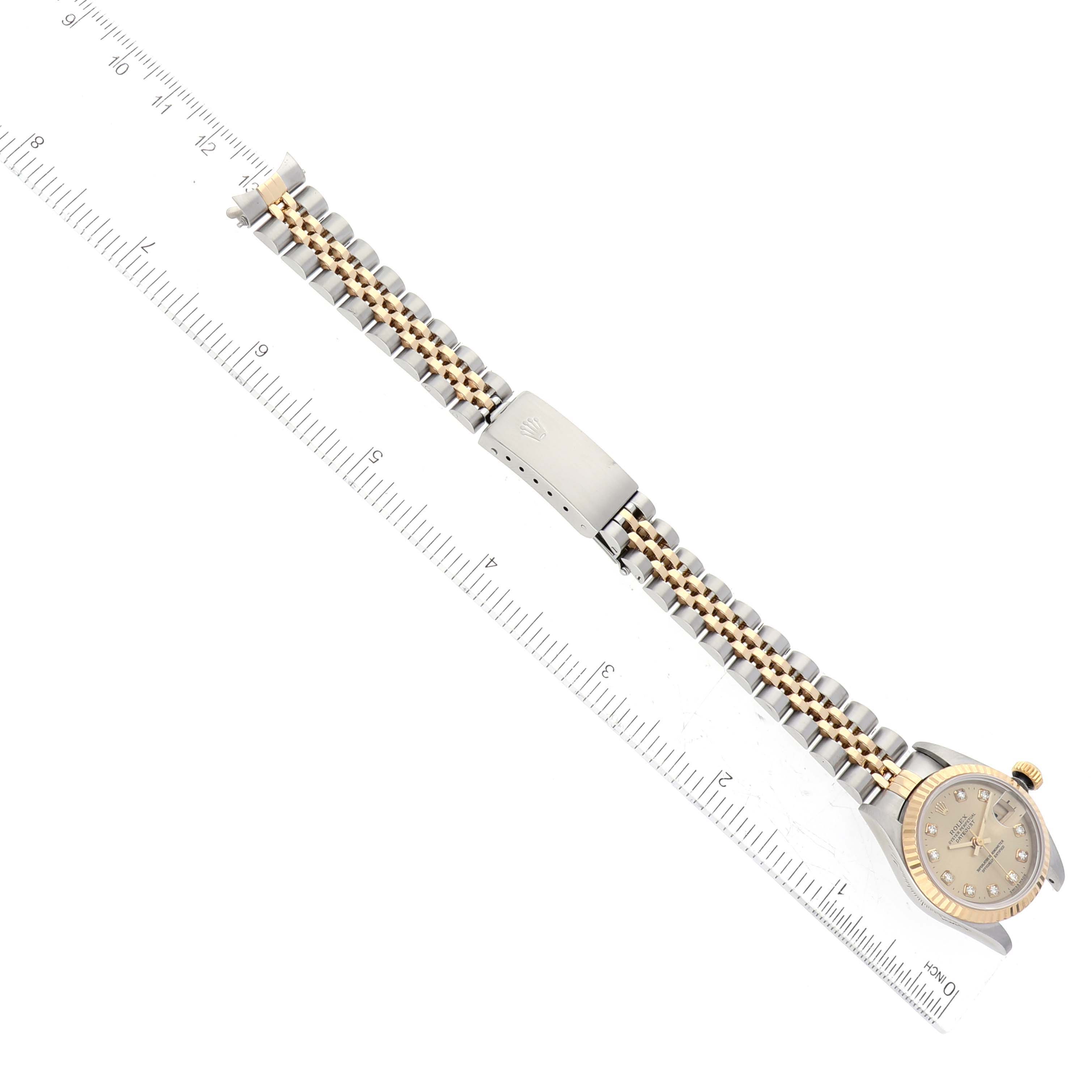 The Rolex Datejust 69173 Women's Steel and Gold (two tone) Champagne Dial 69173 Women's Steel and Gold (two tone) Champagne Dial watch is shown from an overhead angle, highlighting the dial, bezel, and bracelet next to a ruler for scale.