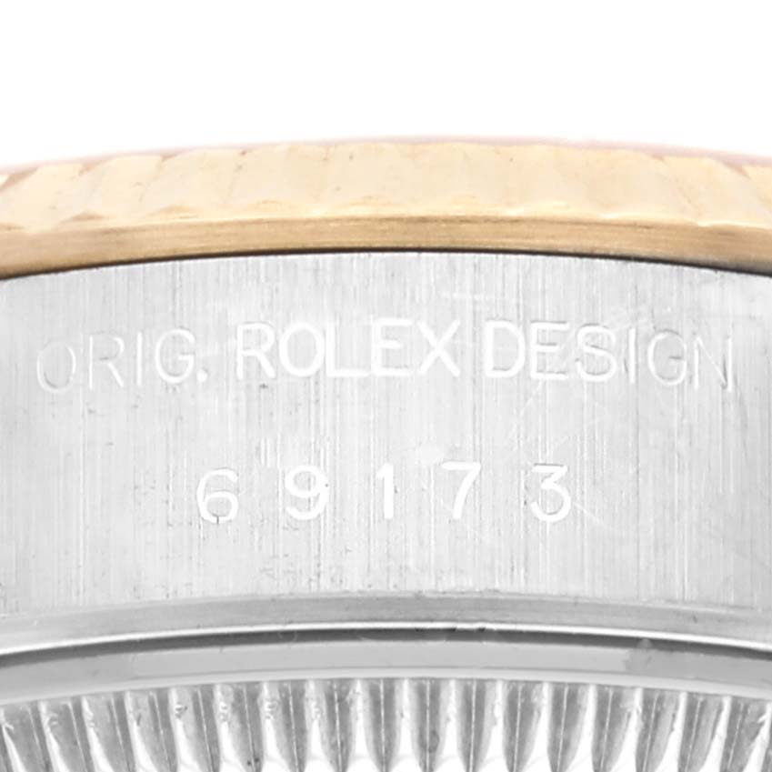 This close-up image shows the side of a Rolex Datejust 69173 Women's Steel and Gold (two tone) Champagne Dial 69173 Women's Steel and Gold (two tone) Champagne Dial watch case with its engraved model number and "ORIG. ROLEX DESIGN" text.