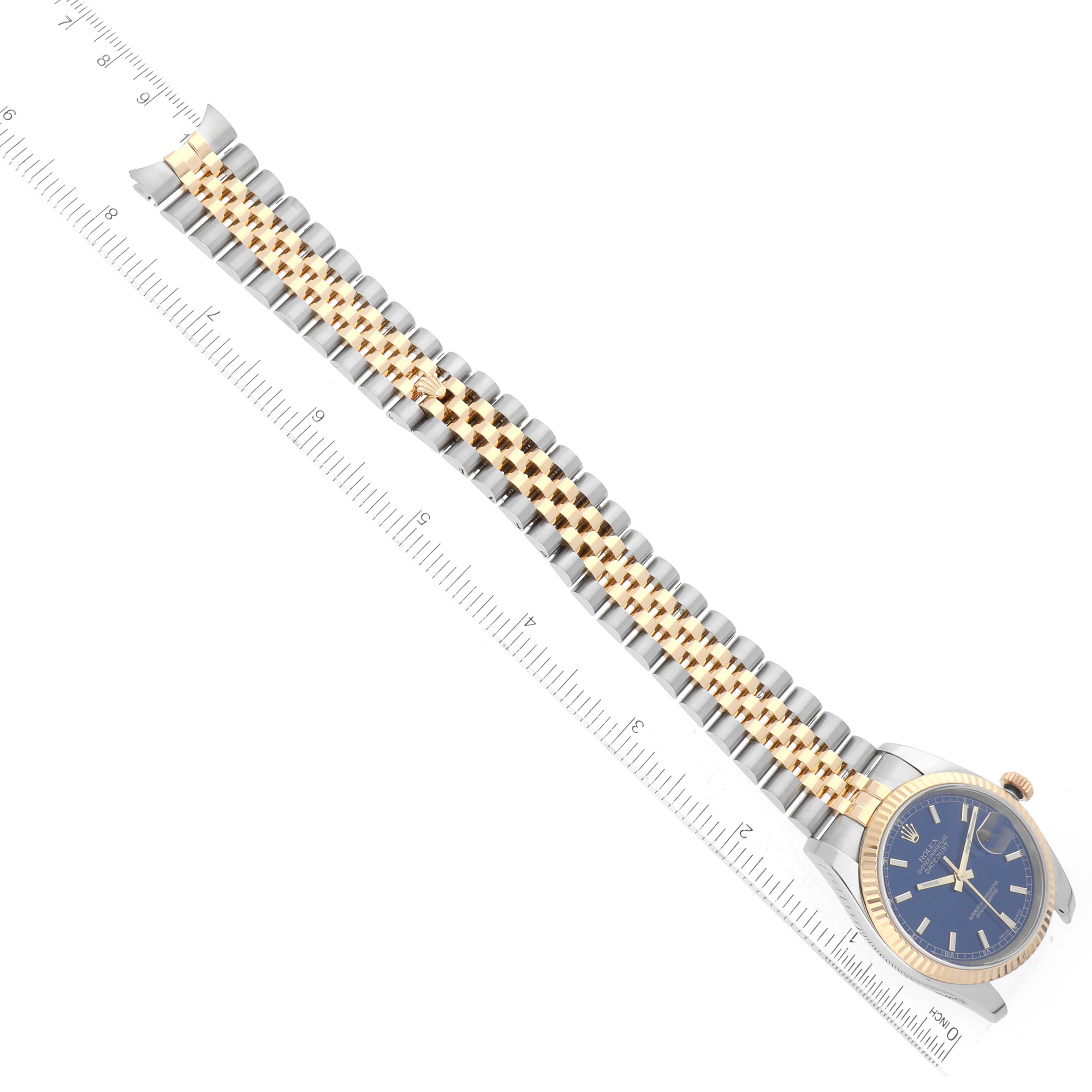 The Rolex Datejust 116233 Men's Steel and Gold (two tone) Blue Dial watch is shown from an aerial view, highlighting the bezel, blue dial, and two-tone jubilee bracelet with a ruler for scale.