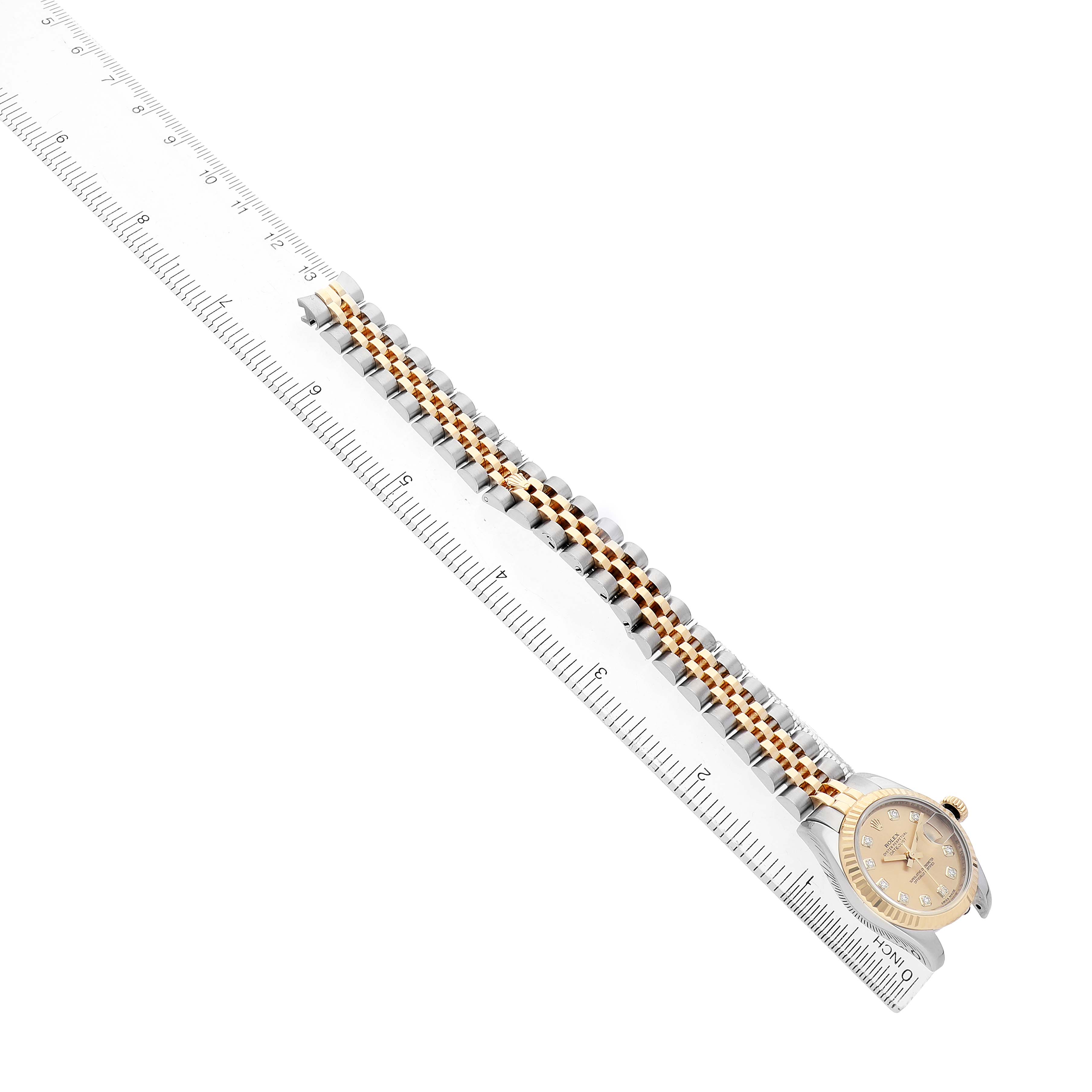 The Rolex Datejust 179173 Women's Steel and Gold (two tone) Champagne Dial watch is shown at a slight angle, highlighting its face, bezel, and full bracelet alongside a ruler for scale.